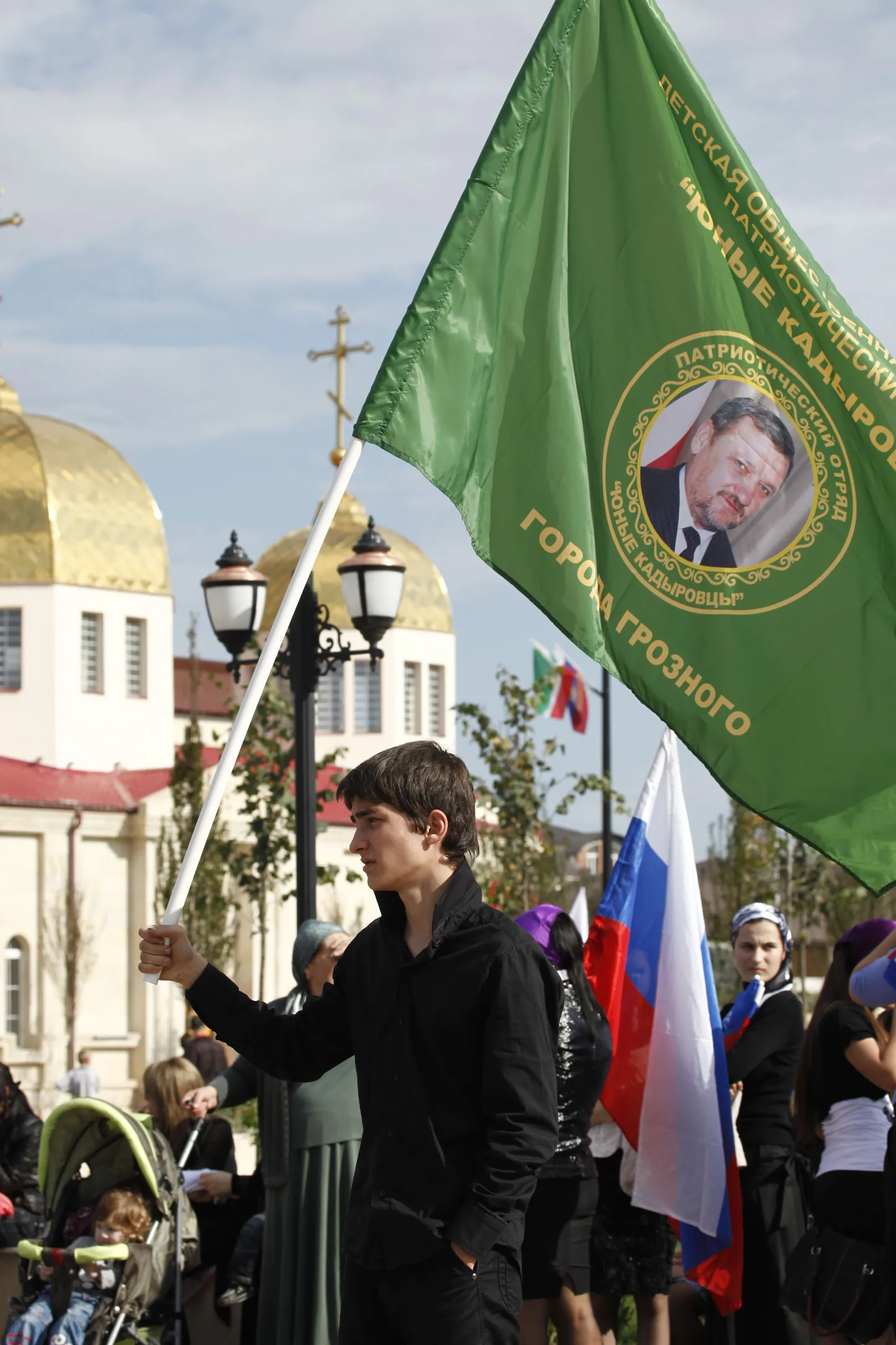 "Юный кадыровец" несет флаг с портретом Ахмата Кадырова