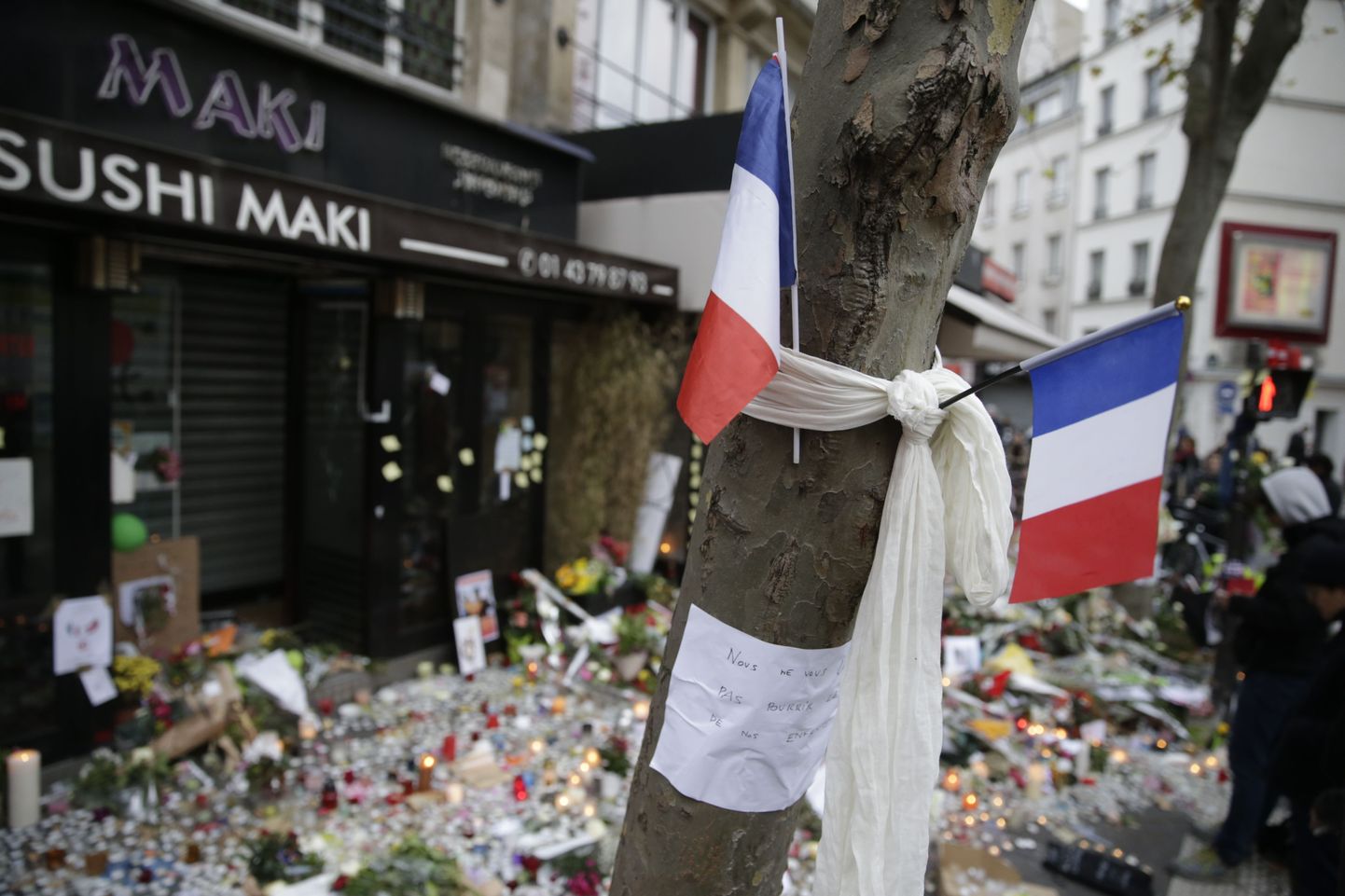 French flags and a note reading "We will not let you spoil our children's lives" at the site of the attack at the Cafe Belle Equipe on rue de Charonne in the 11th district, early on November 16, 2015 in Paris, three days after the terrorist attacks that left over 130 dead and more than 350 injured. France prepared to fall silent at noon on November 16 to mourn victims of the Paris attacks after its warplanes pounded the Syrian stronghold of Islamic State, the jihadist group that has claimed responsibility for the slaughter.  AFP PHOTO / KENZO TRIBOUILLARD