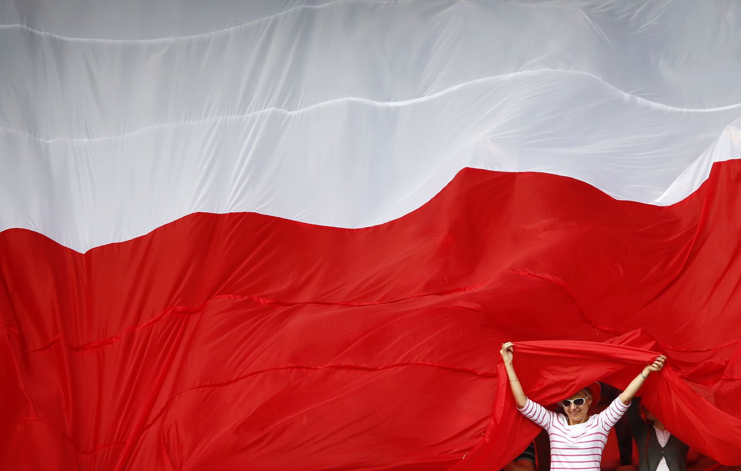 Supporters of Poland's national soccer team are seen under a large Polish flag as they wait for the start of a practice session one day after their Euro 2012 opening soccer match in Warsaw June 9, 2012.  REUTERS/Kai Pfaffenbach (POLAND  - Tags: SPORT SOCCER)