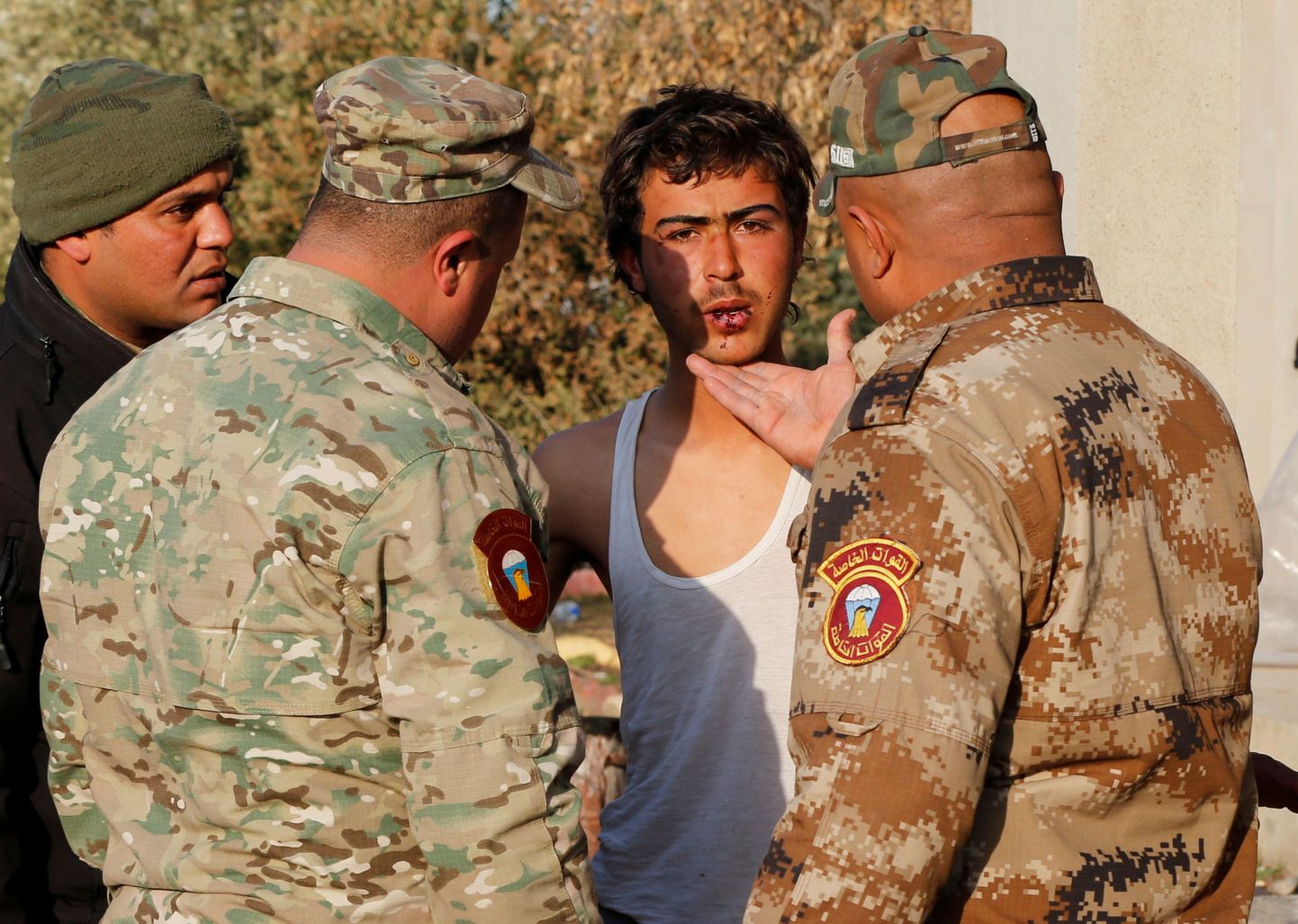 Iraagi sõdurid kahtlusalust ISISe võitlejat küsitlemas.