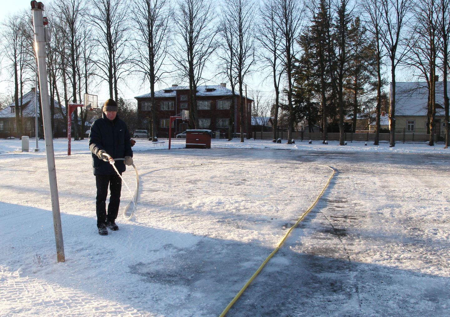 Pildil uisuplatsi rajamine Tamme staadionil. Voolikust kastab jääväljakut sihtasutuse Tartu Sport haldusjuht Mati Tolmoff.