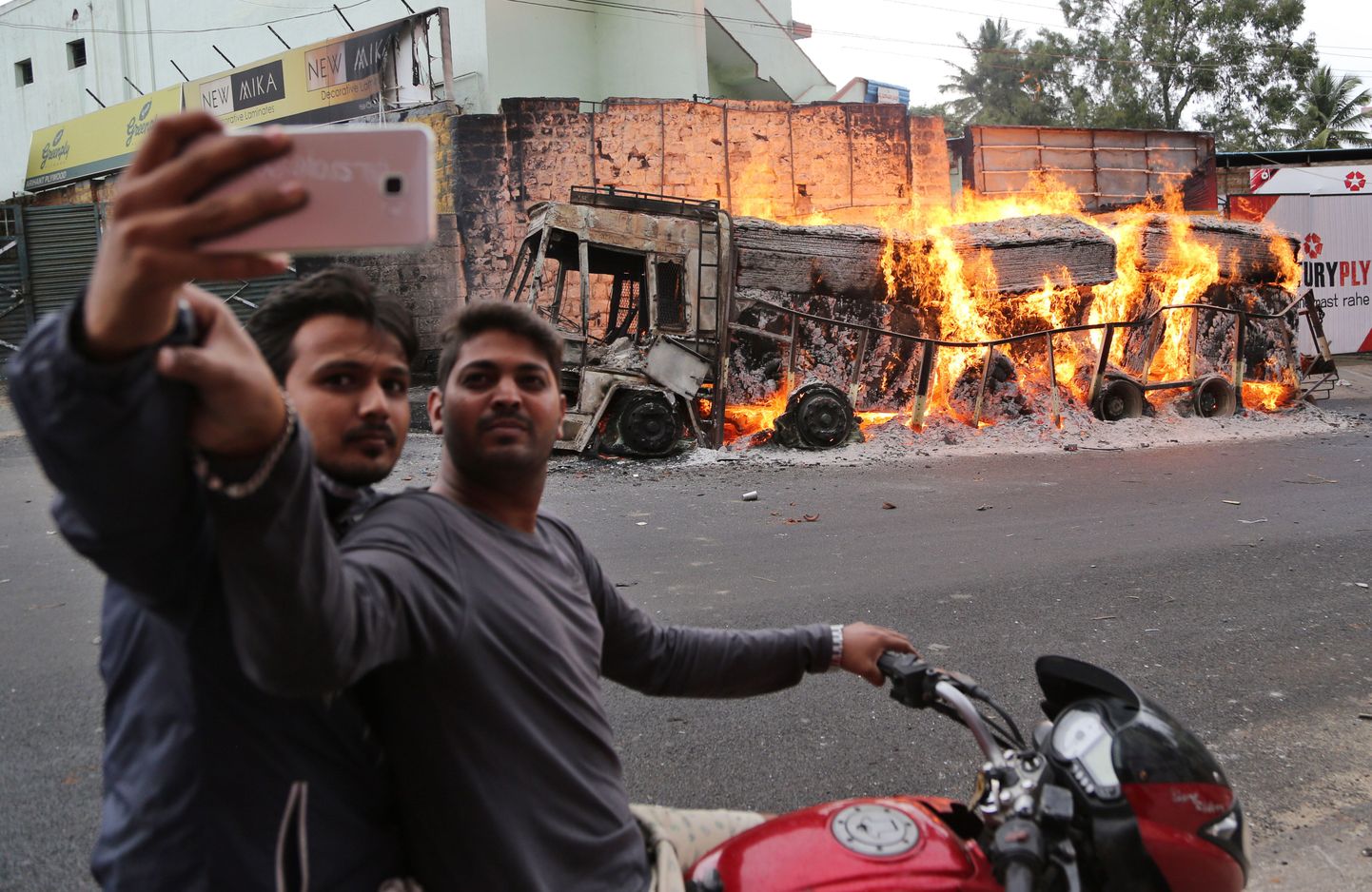 Kaks meest poseerimas Bangalores põleva auto ees.