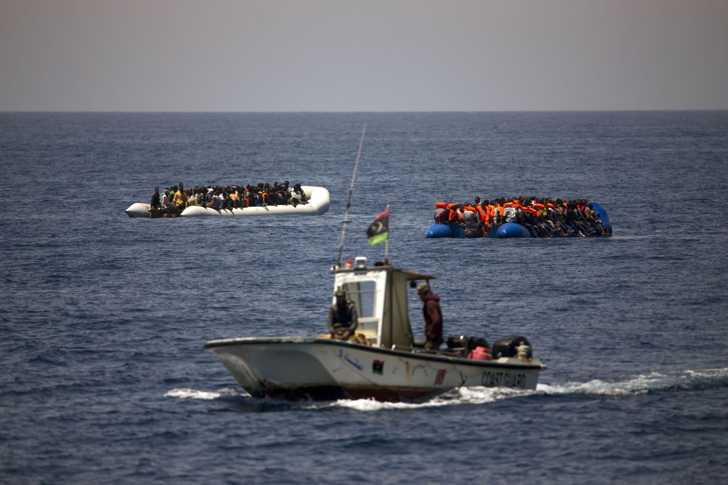 Liibüa rannavalvurid sõitmas mööda migrante täis kummipaatidest Liibüa ranniku lähedal