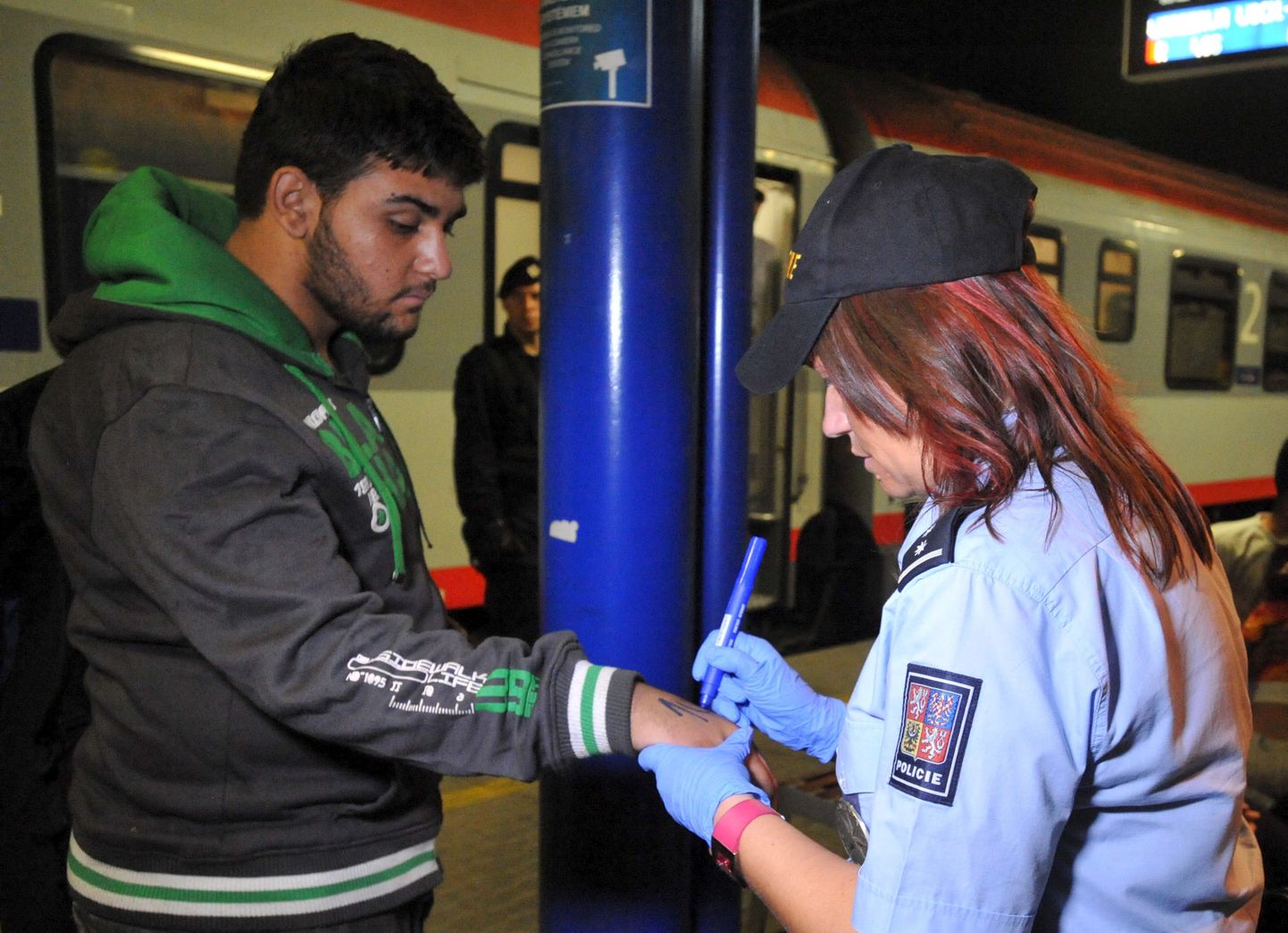 Tšehhi politseinik märgistamas riiki saabunud migranti.