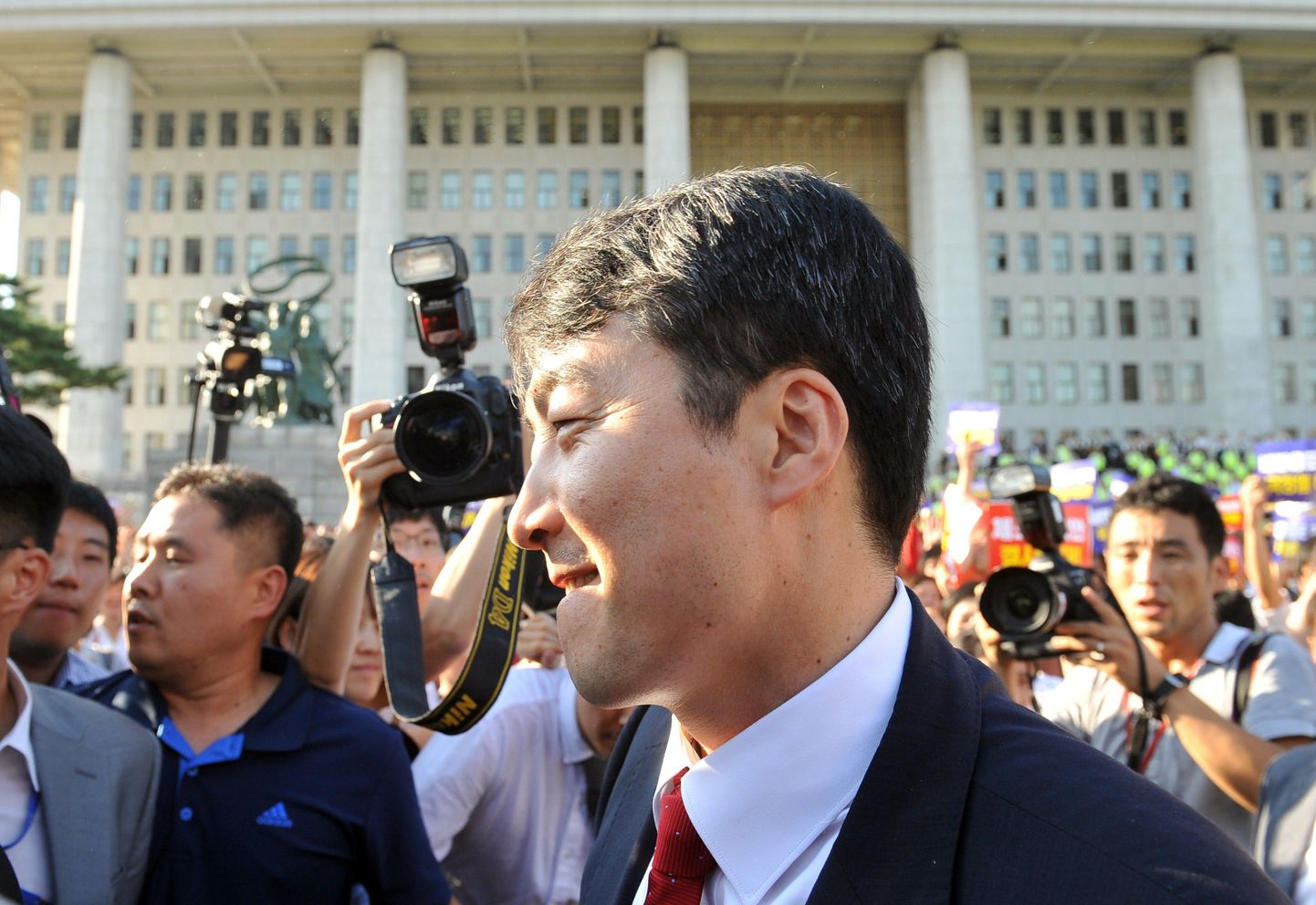 Süüdistatav vasakpoolne parlamendiliige Lee Seok-Ki (keskel) Lõuna-Korea parlamendihoone ees.