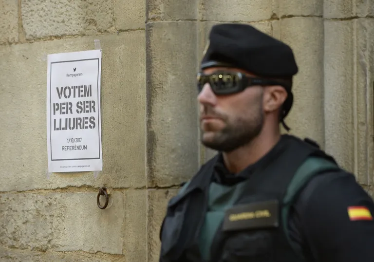 Guardia Civili töötaja iseseisvuslaste plakati kõrval Girona linnas patrullis. Foto: Josep Lago / AFP / Scanpix