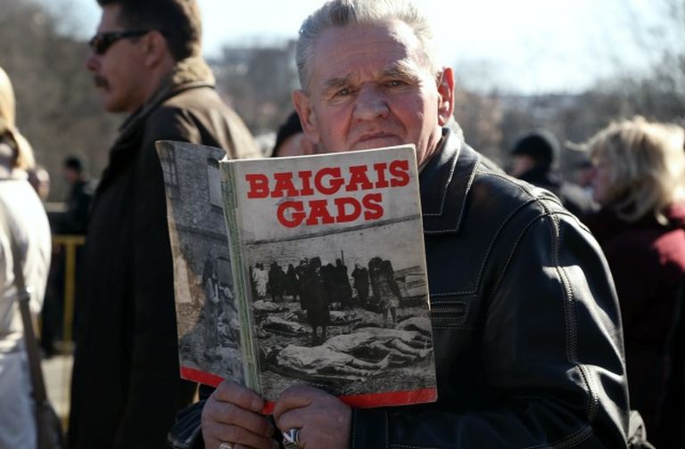 Иллюстративное фото. Мужчина с книгой "Baigais gads" ("Страшный год")  на мероприятии памяти легионеров, 16 марта 2015 года.
