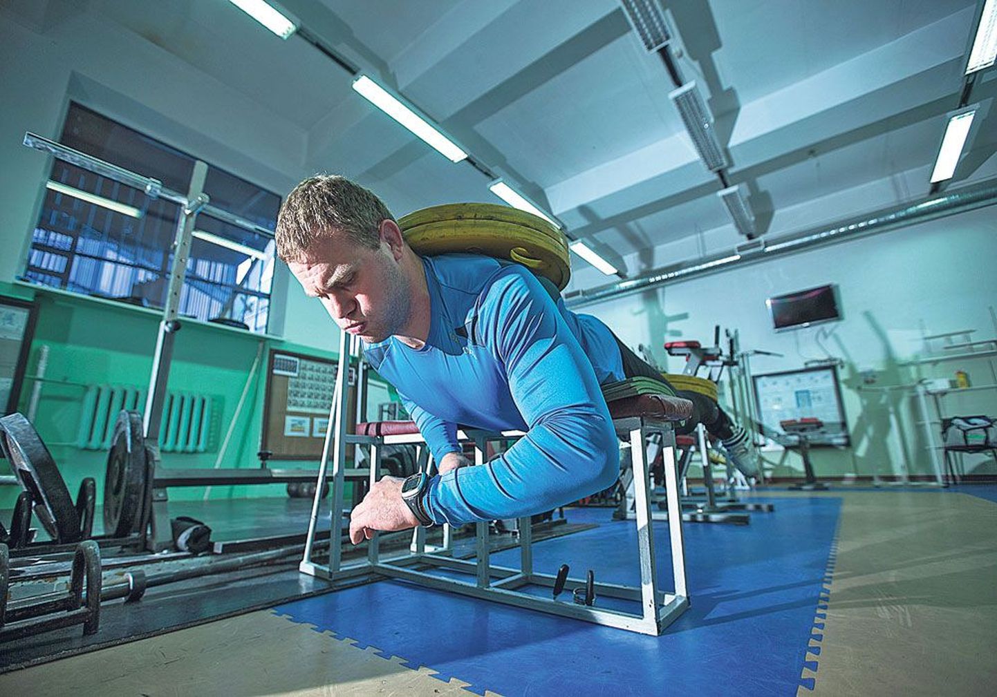 Тренировка накануне ЧМ по борьбе: Хейки Наби смотрит на часы, чтобы вовремя завершить статическое упражнение для спины. На спине и ногах спортсмена диски по 30 кг.