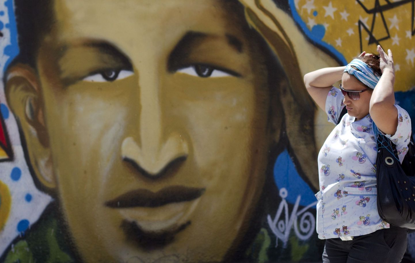 Naine Caracases möödumas seinamaalingust, millel on kujutatud Venezuela presidenti Hugo Chávezt.