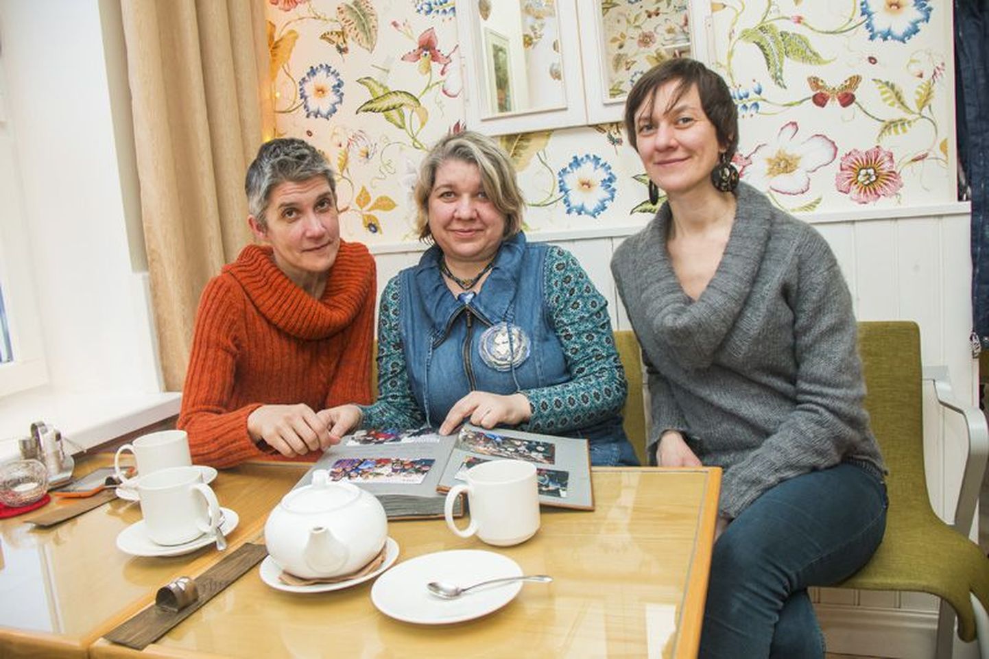 Kolm õde kohvikus: Mari (vasakult), Erika ja Kadri keeravad lehti albumis, kus on enam kui kolmekümne aasta perefotod, mis saadetud pühadetervitusteks sõpradele-sugulastele.
