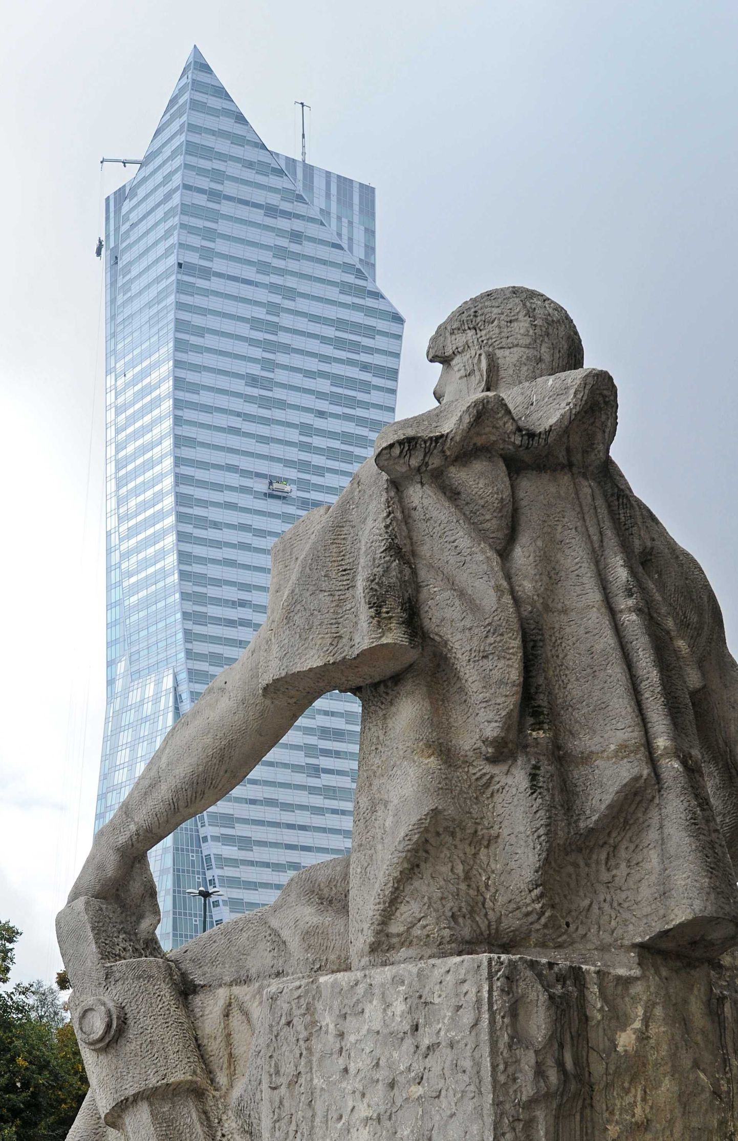 Kommunismiaegne monument ja moodne kõrghoone selle taustal Varssavis.