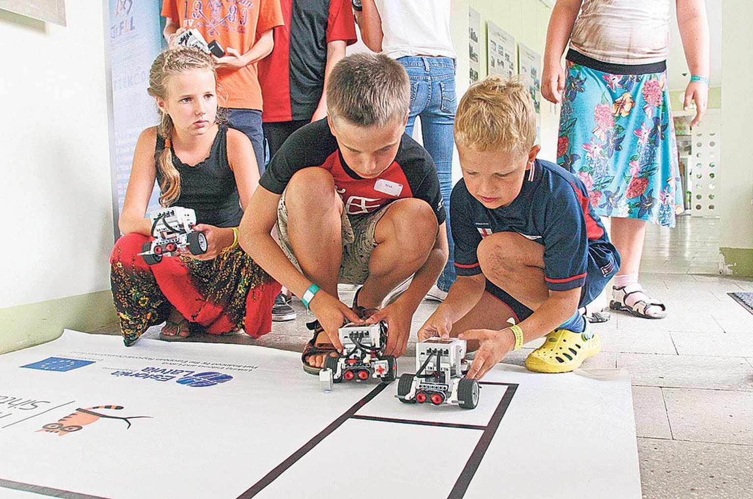 «On väga oluline, kuidas te roboti asetate. Kui panete ta alguses viltu, siis ta sõidab ka viltu,» rääkis juhendaja. Oma roboti võimekust katsetavad Vivian (10, vasakult), Mikk (11) ja Alex Sander (9).