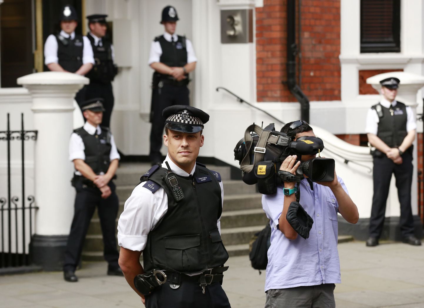Briti politseinikud ning ajakirjanikud ootavad Ecuadori saatkonna ees Julian Assange'i väljumist.