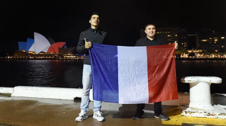 Kaks prantslast kodumaa lipuga täna kaastunde märgiks samuti Prantsuse trikoloori värvides valgustatud Sydney ooperimaja ees.