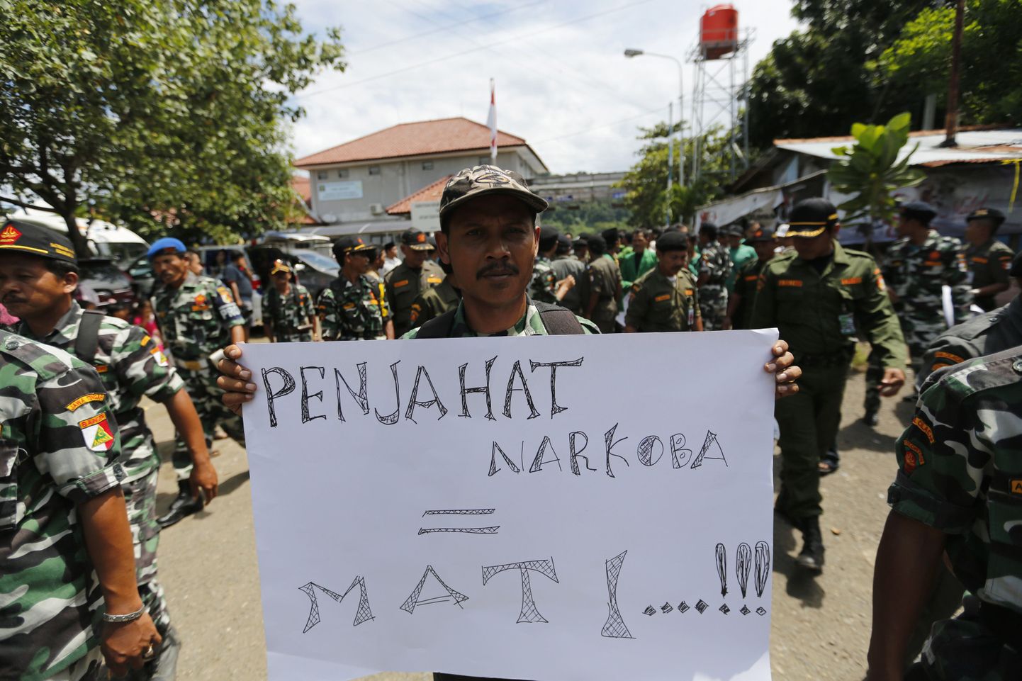 Narkokurjategijatele surmanuhtlust nõudva plakatiga mees vangla ees.