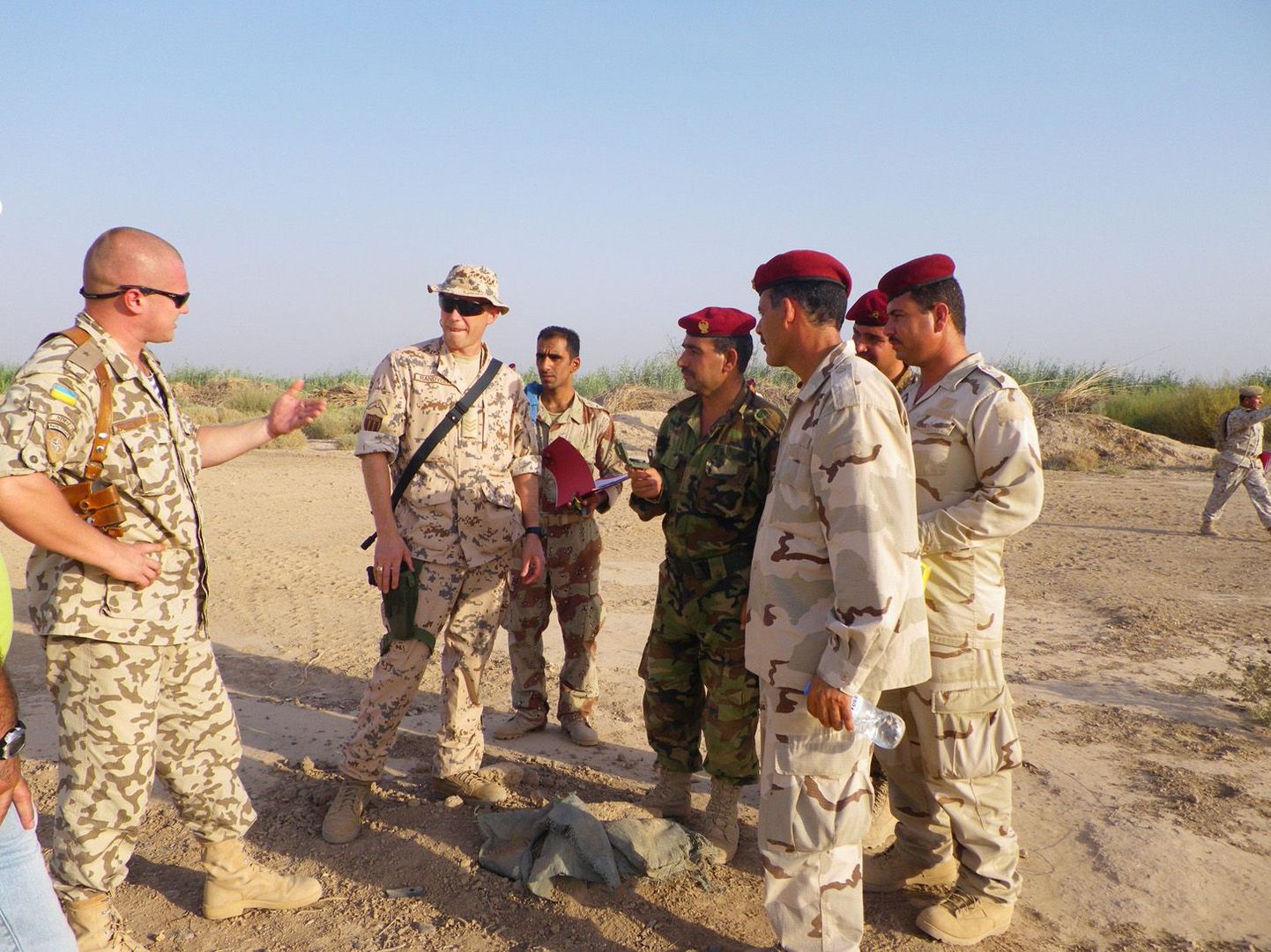 NATO väljaõppemissioonil teeninud Ukraina ohvitser, Rando Randveer ja Iraagi sõjaväelased orienteerumise õppimiseksks kasutatud lagedal platsil.