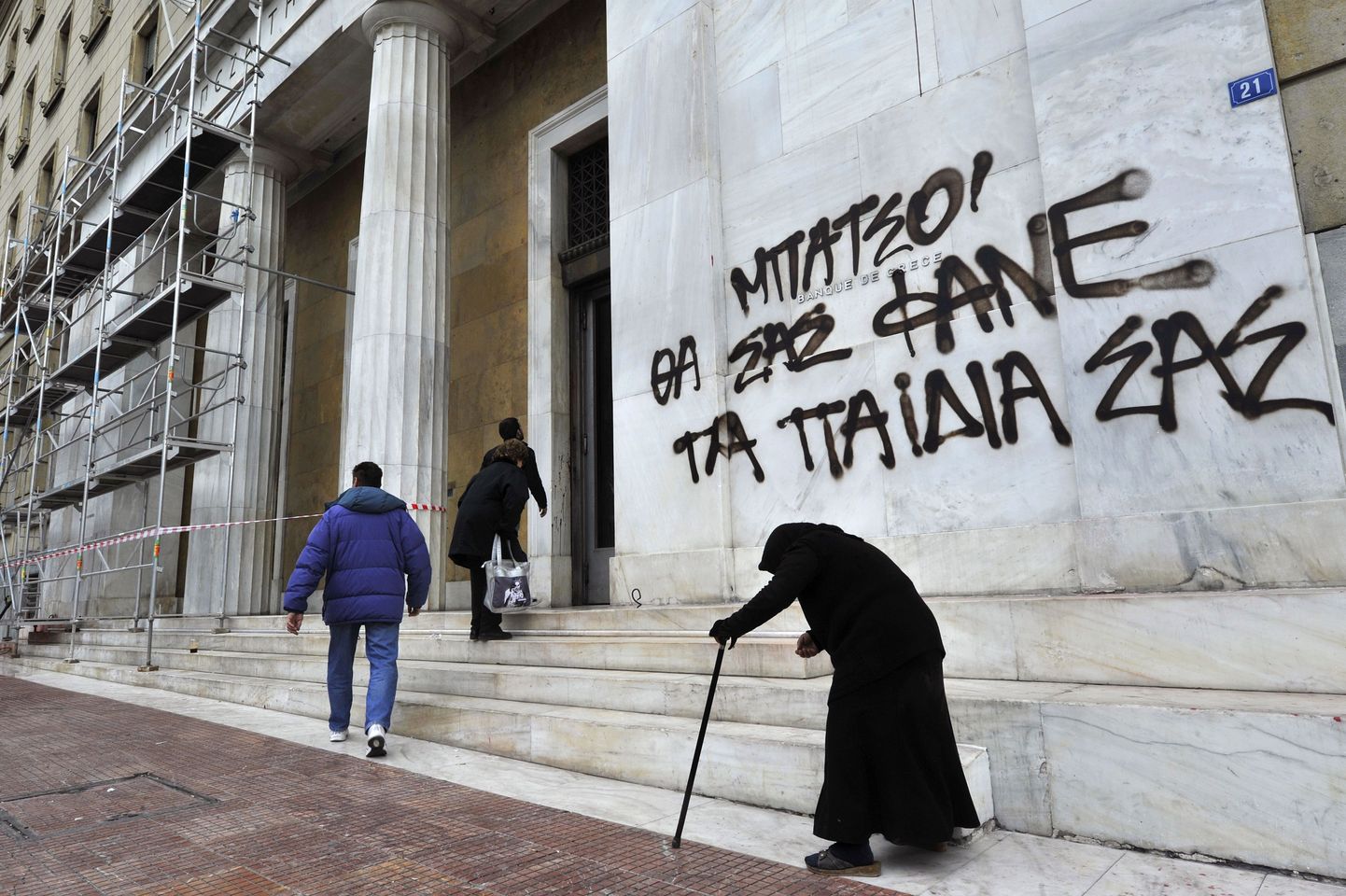 Vanem naine eile Ateenas Kreeka panga peakorteri ees kerjemas.