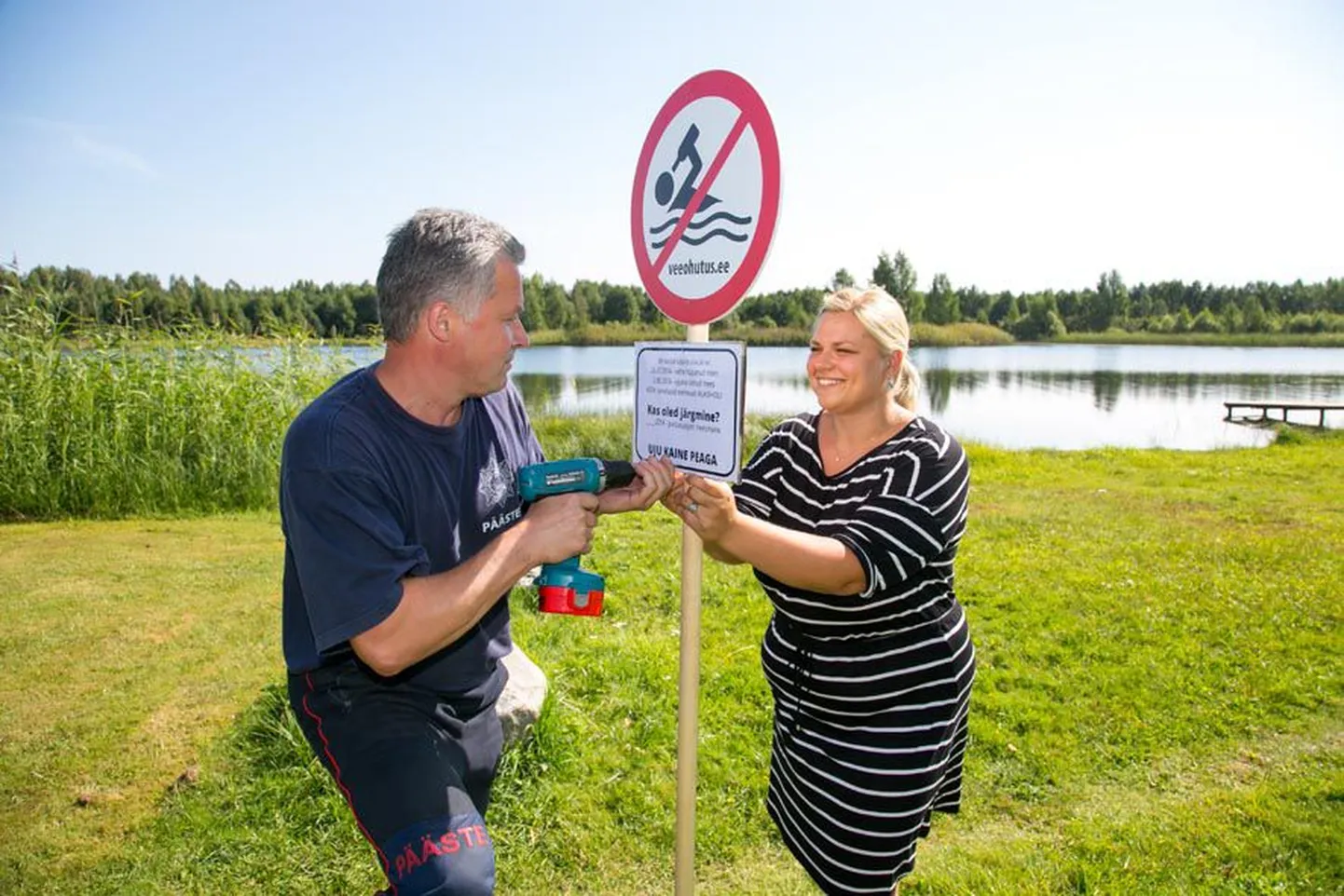 Päästeameti ennetustöö spetsialist Kätlin Poopuu ja Türi päästja Arvi Pitelkov kruvivad keelumärgi külge teadetetahvli, mis annab teada, et selles järves on tänavu uppunud juba kaks inimest.