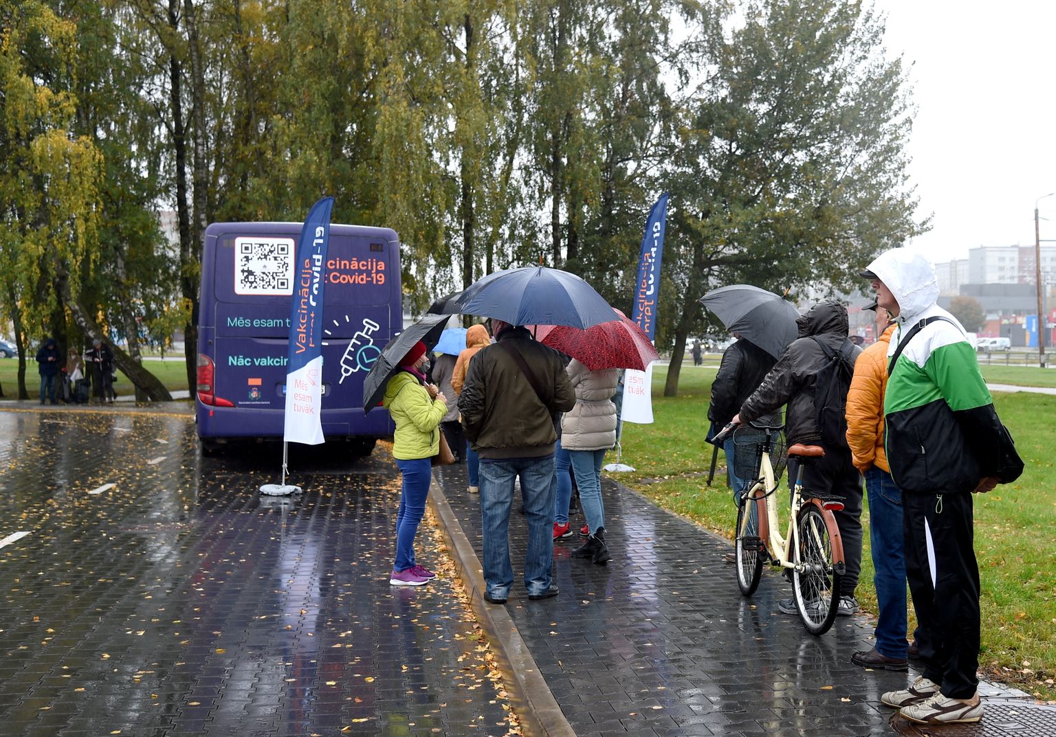 Cilvēki ieradušies saņem poti pret Covid-19 izbraukuma vakcinācijā speciāli pielāgotajā autobusā stāvlaukumā.