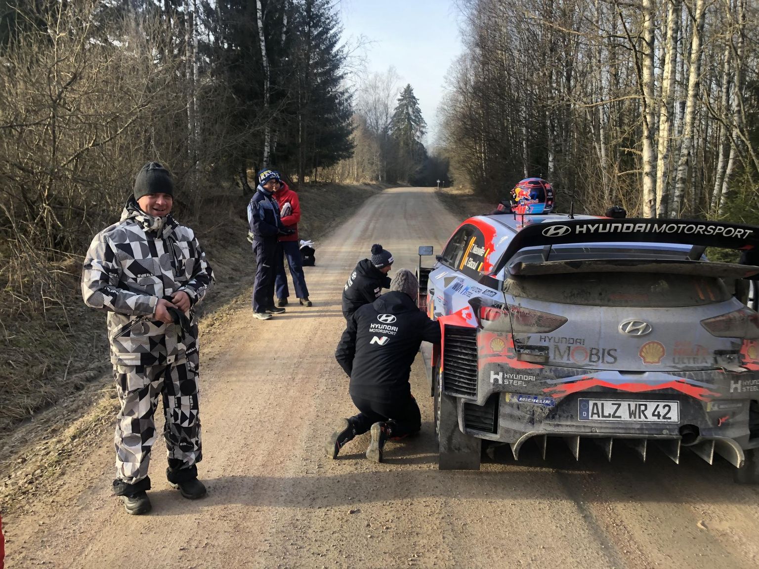 Marek Tammoja (vasakul laigulises kombinesoonis) tänavusel Rootsi rallil stardiaega ootava Thierry Neuville'i auto kõrval.