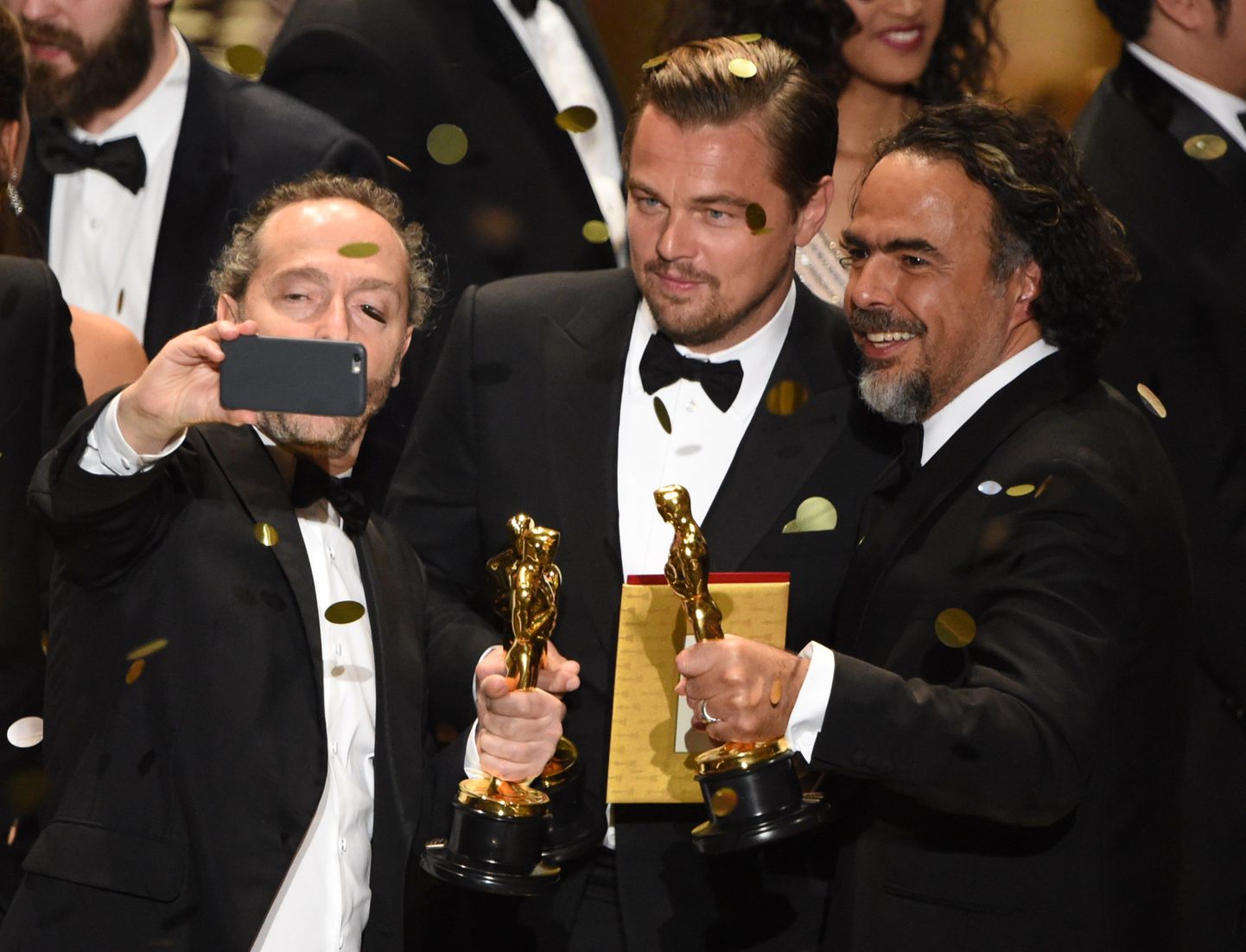 Cinematographer Emmanuel Lubezki (L) , Actor Leonardo DiCaprio (C) and Director Alejandro Gonzalez Inarritu take a selfie with their awards on stage at the 88th Oscars on February 28, 2016 in Hollywood, California. AFP PHOTO / MARK RALSTON