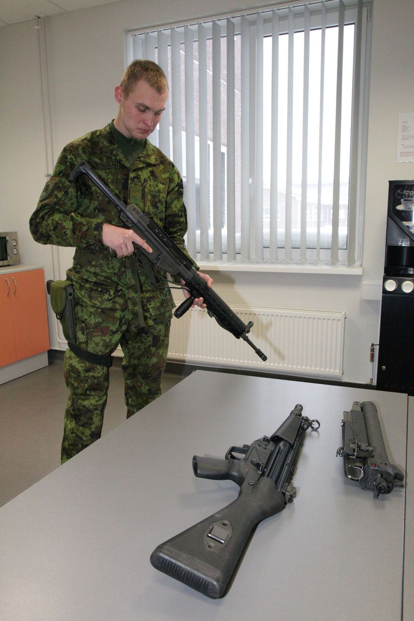 Nooremleitnant Harri-Mait Kreitsmann hoiab käes Norrast saabunud moderniseeritud automaati AG3 F2, laual on püstolkuulipilduja MP5 ja relvale kinnitatav granaadiheitja.