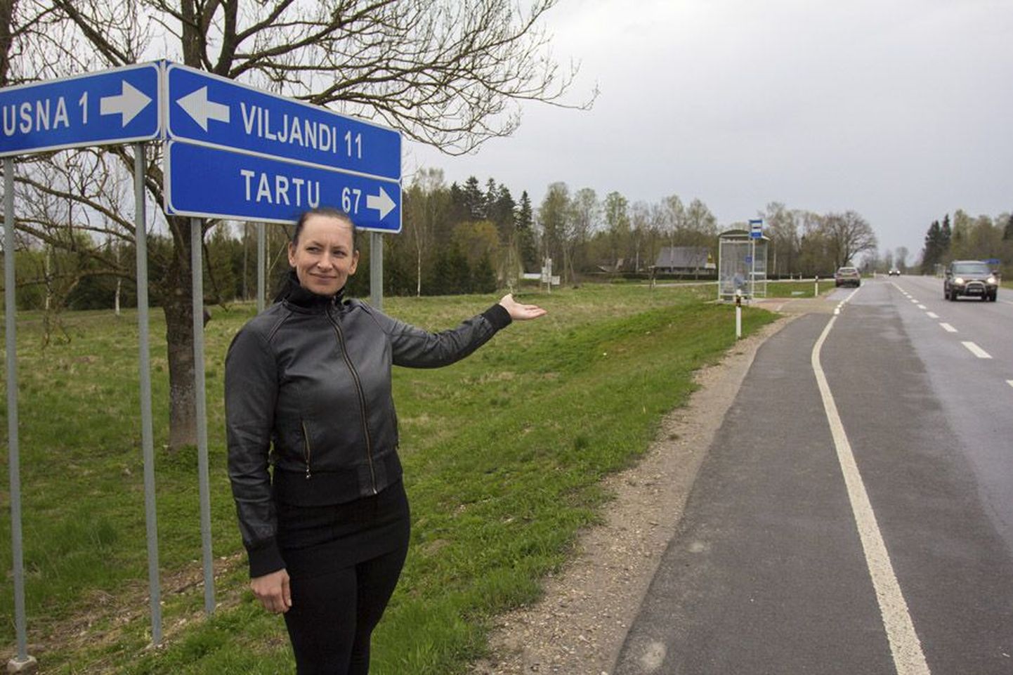 Allkirjade kogumise algataja Eha Lepa seisab Tartu maanteel Uusna teelõigu lähedal ja näitab, et kergliiklustee peaks kulgema sellest kohast Kaunismäe kaupluseni, kust läheb edasi varem valminud teejupp.