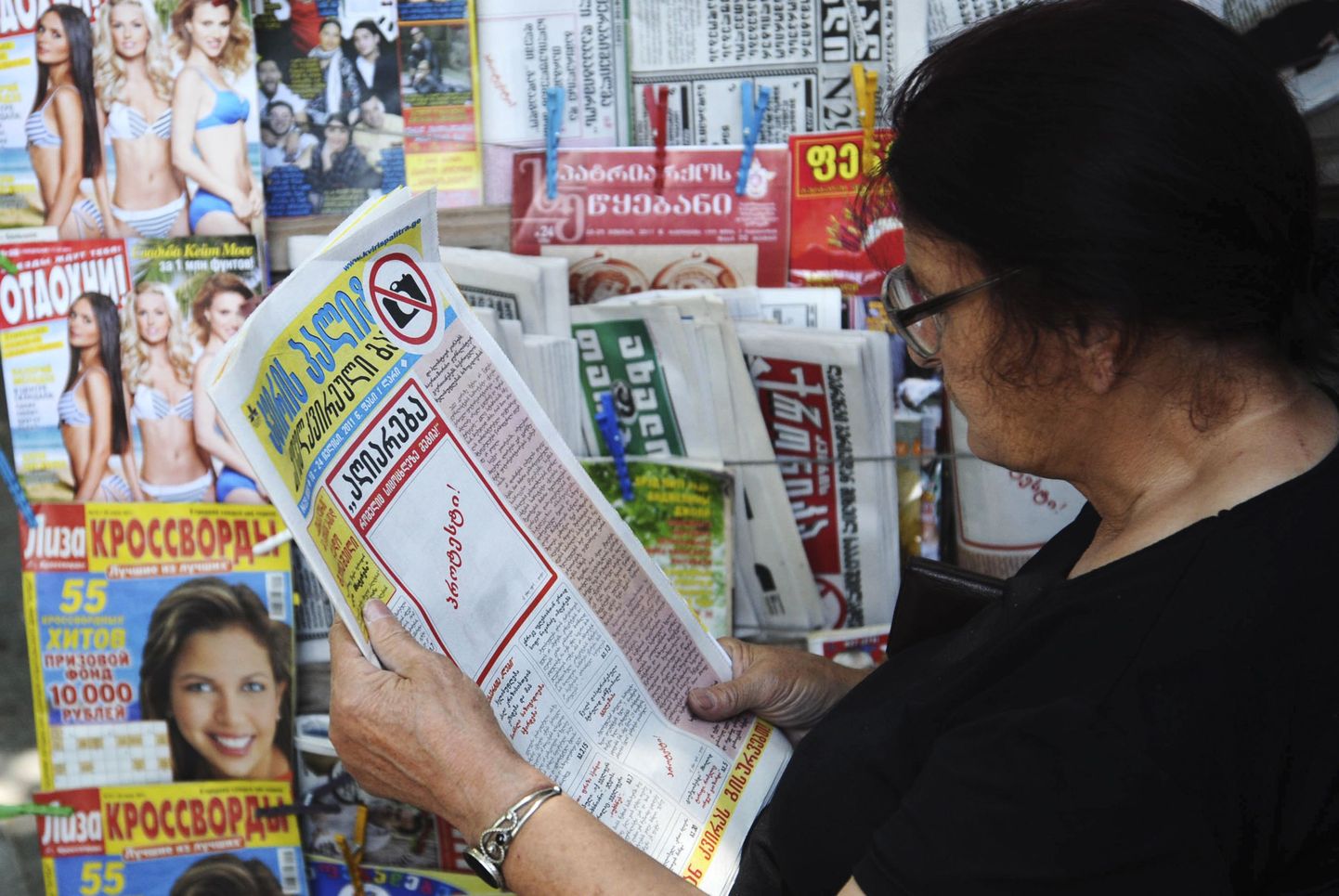 Женщина держит газету без фотографии на первой полосе.
