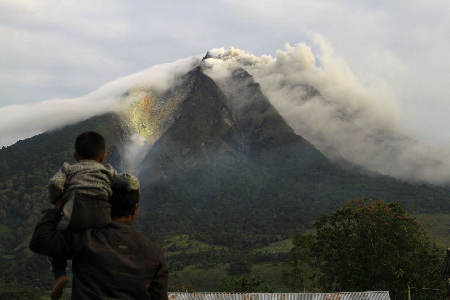 Mees ja tema poeg vaatavad Sinabungi vulkaani purset.