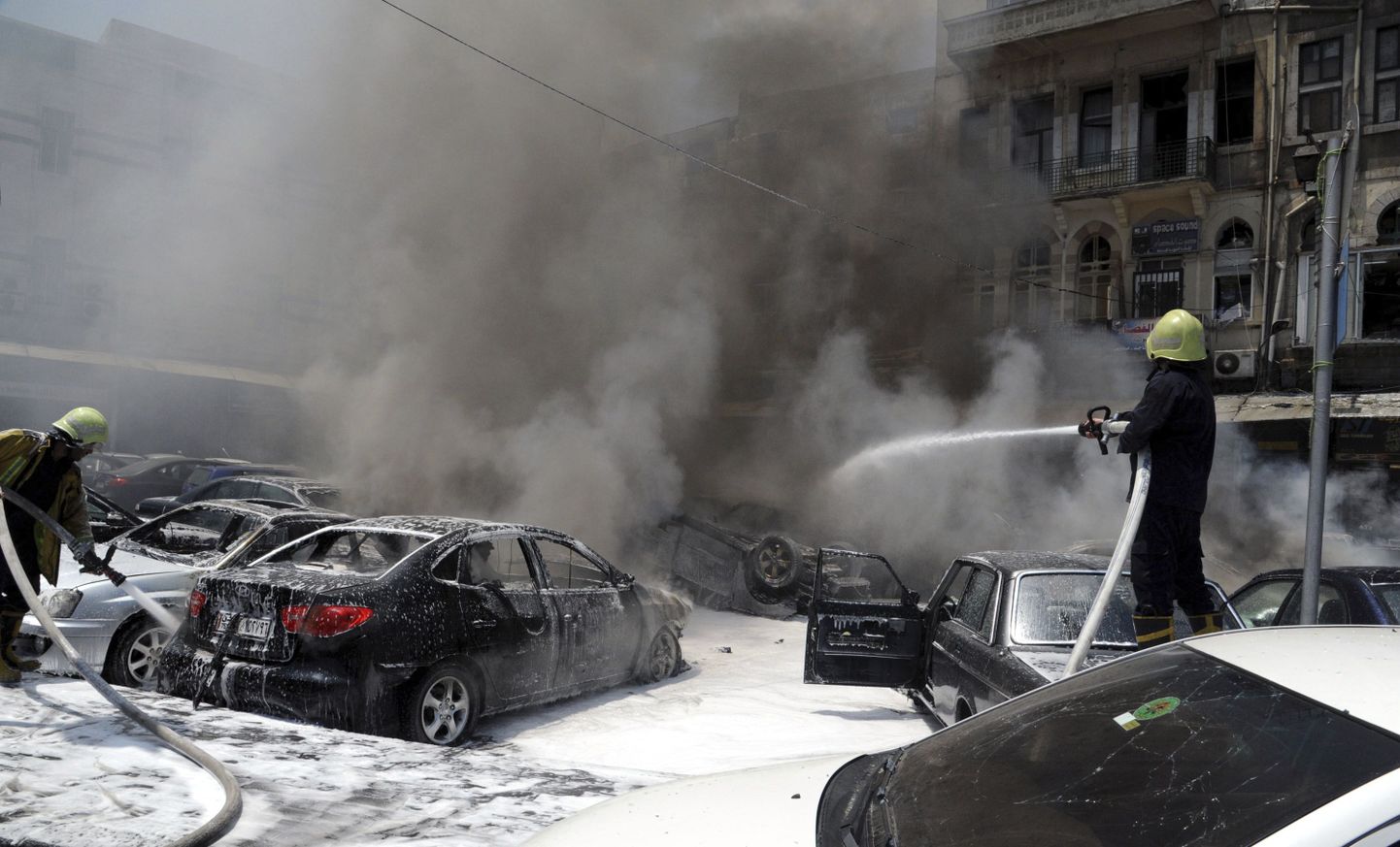 Tuletõrjujad kustutavad põlevaid autosid pärast Damaskuse Õiguspalee parklas toimunud plahvatusi 28. juunil