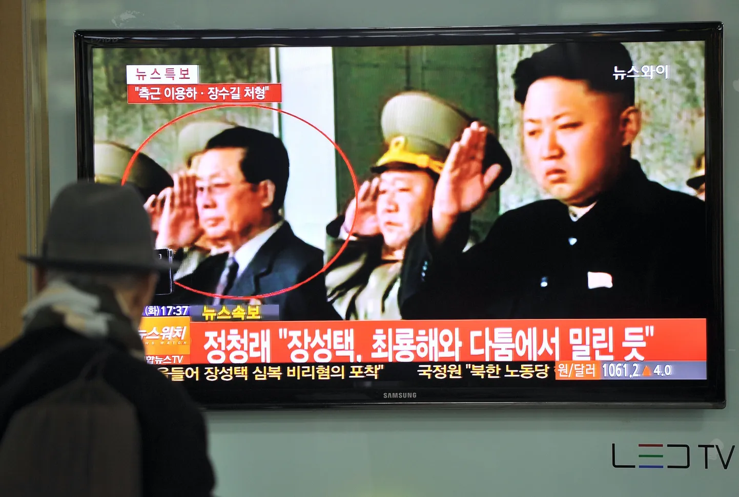 Lõuna-Korea mees vaatab teleriekraanilt fotot Põhja-Korea liidrist Kim Jong-unist (paremal) ja tema onust Jang Song-thaekus (vasakul sõõri sees).