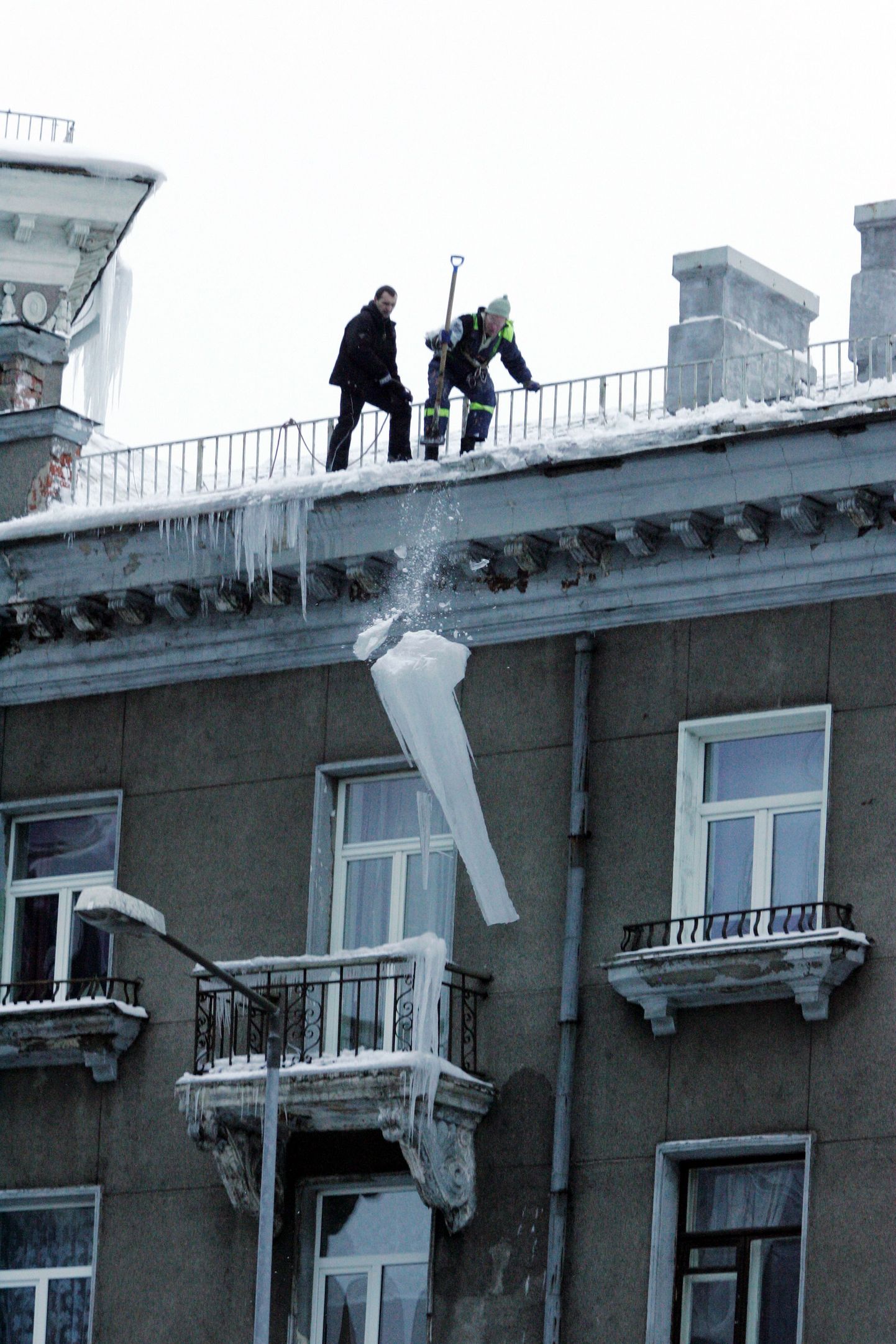Töömehed eemaldasid Tartu maantee ja Liivalaia tänava nurgal asuva maja katuselt lume ja kõnnitee kohal varitsenud mitme meetri pikkuseid jääpurikaid.