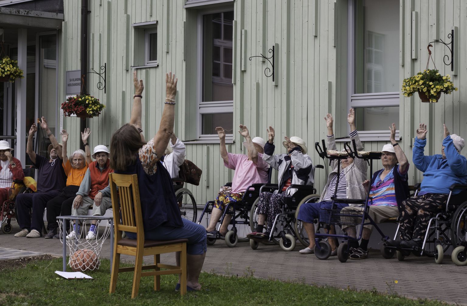 Hoolekandekeskuse elanikud suvisel spordipäeval palliharjutust õppimas.