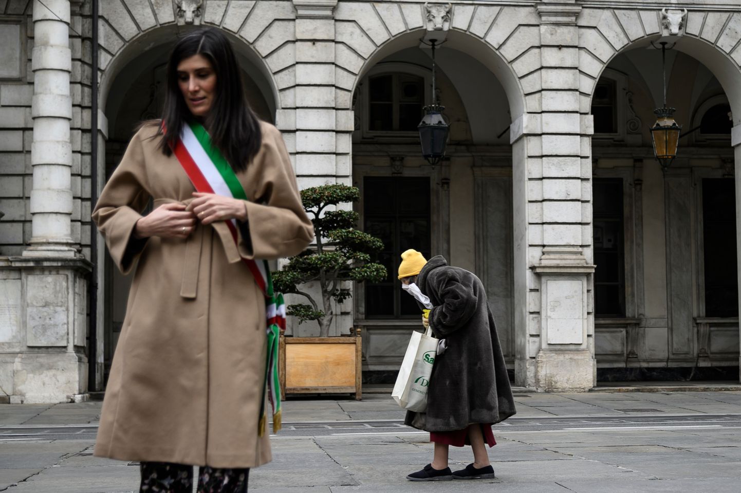 31.märts 2020, Turin, Itaalia. Linnapea Chiara Appendino seisatab vaikuseminutiks, mil linn mälestab viiruseohvreid, taustal kõnnib eakas Itaalia kodanik.