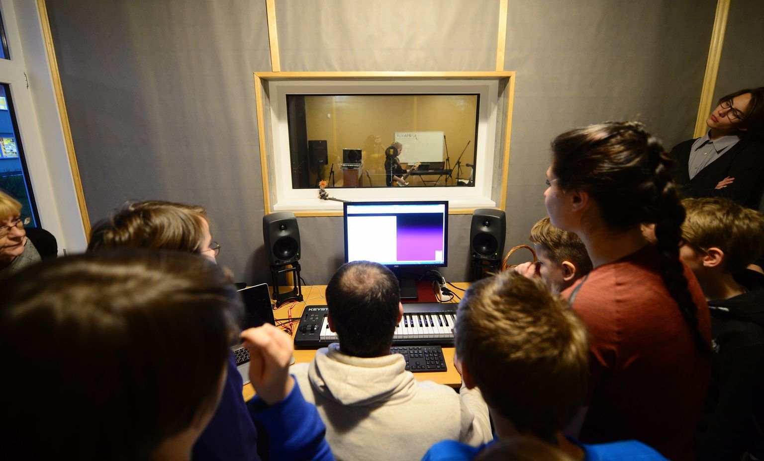 Tartu II muusikakooli õpilased uudistavad foonika aparatuuri. Aknakesest paistab stuudioruum.