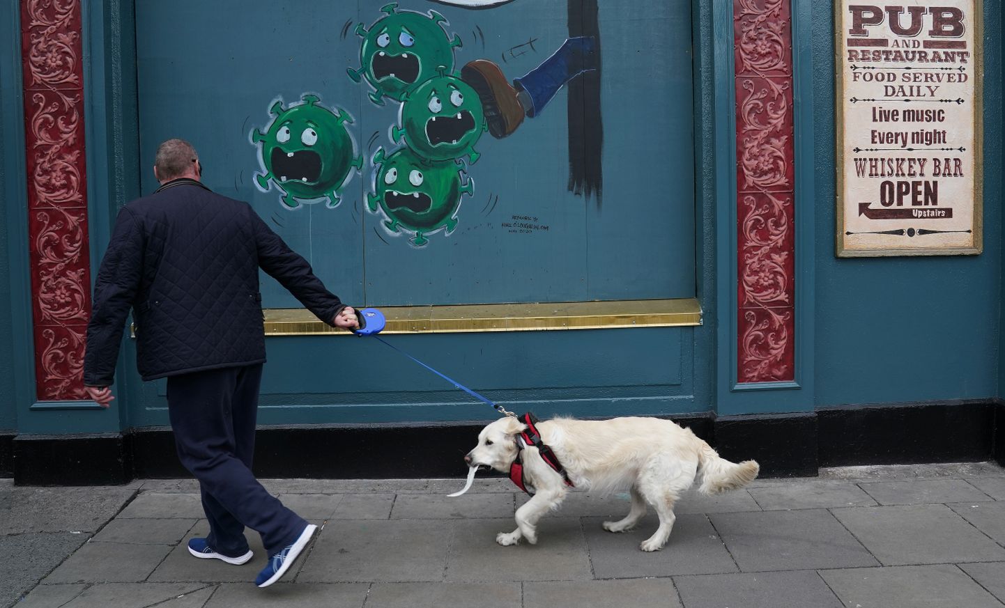 Mees koeraga Dublini suletud pubi eest möödumas.