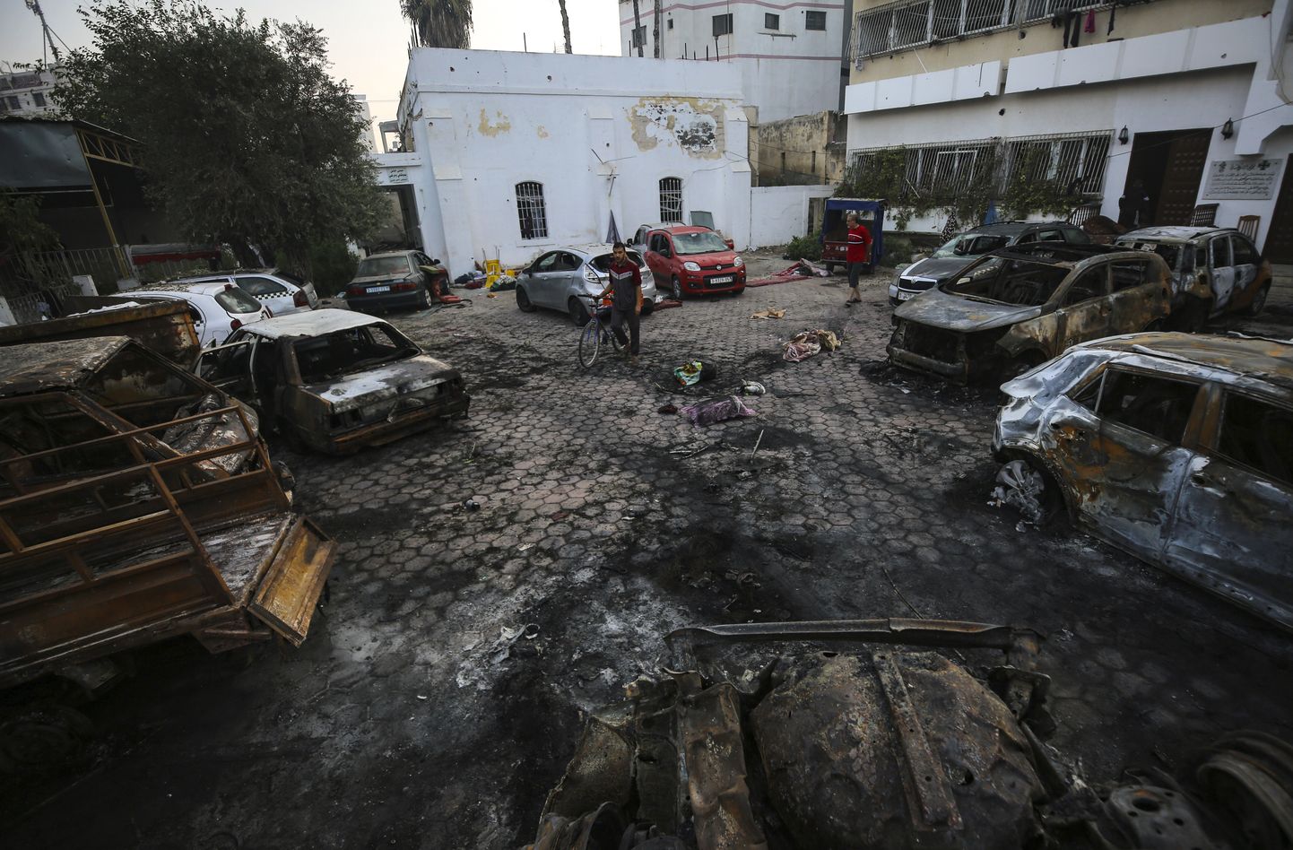 Палестинцы осматривают место взрыва в больнице Аль-Ахли в городе Газа, среда, 18 октября 2023 г.