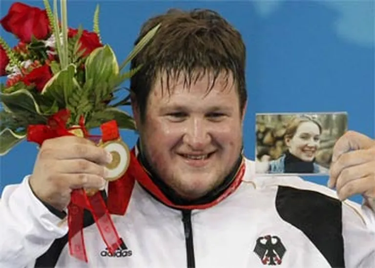 Pekinas olimpisko spēļu čempions Matiass Šteiners no Vācijas demonstrē zelta medaļu un savas bojā gājušās sievas fotogrāfiju. 