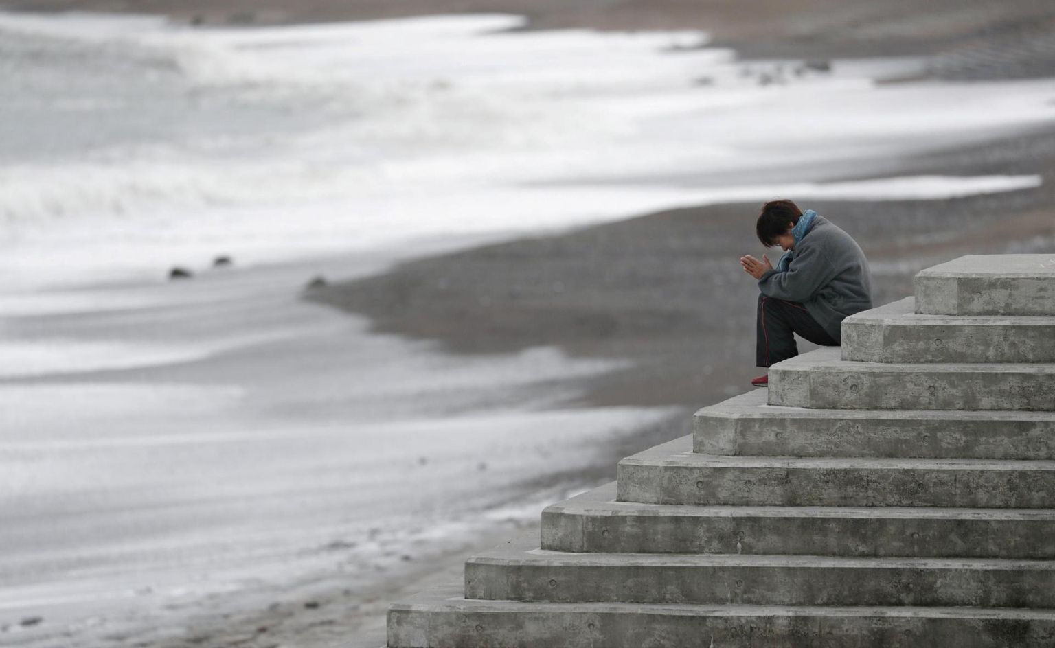 Jaapani naine palvetamas mere poole, mälestades Jaapani kolmikkatastroofi ohvreid.