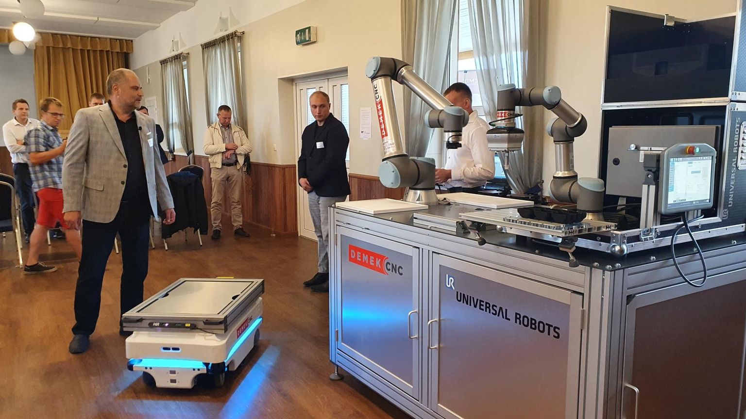Konverentsil Navi seltsimajas sooritasid robotid osalejate silme all ja Demek CNC OÜ juhatuse esimehe Peeter Sekavini (ees vasakul) juhtimisel lihtsamaid puidutööstuse operatsioone.