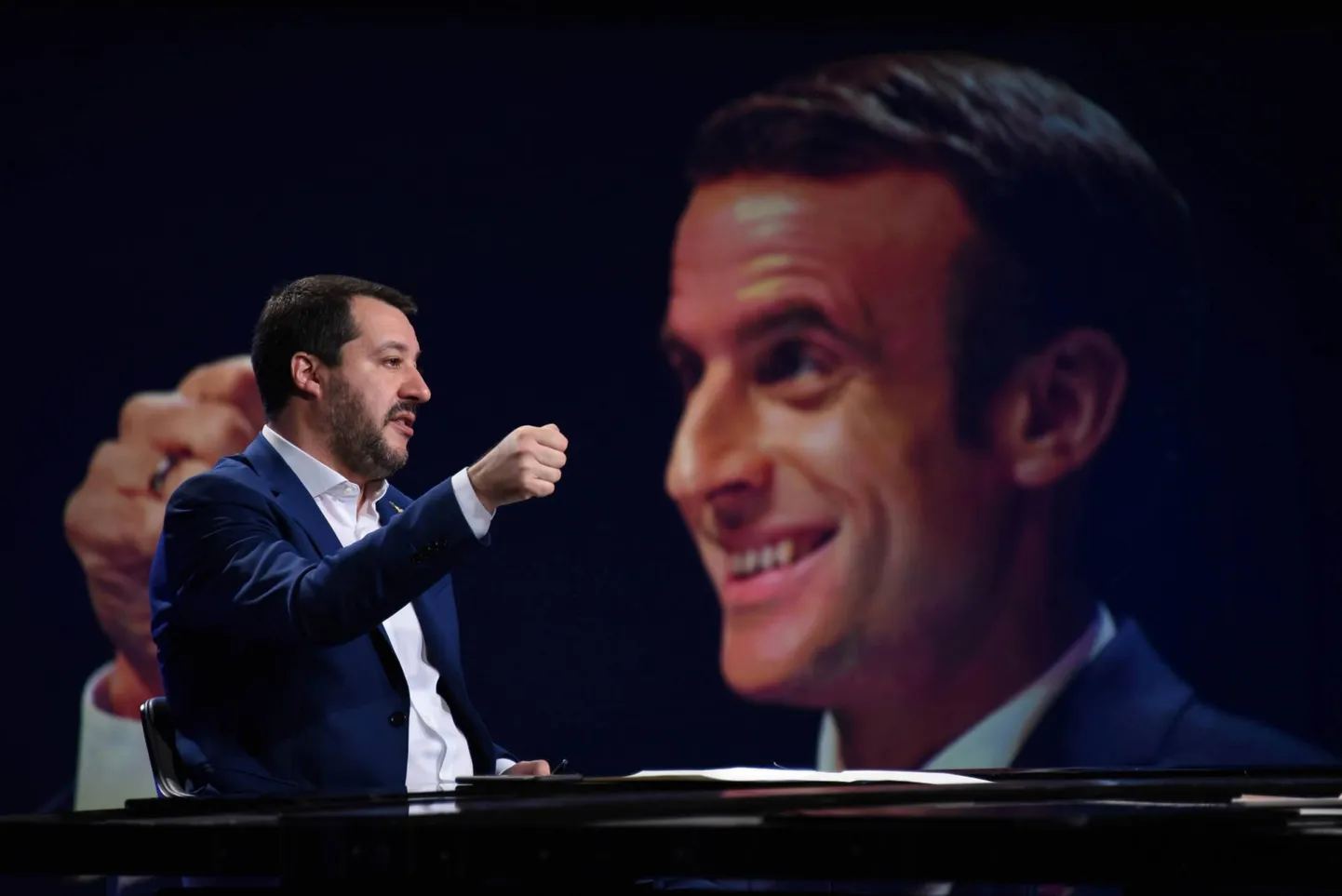 Itaalia siseminister Matteo Salvini (vasakul) televisioonis esinemas. Taustal Prantsusmaa president Emmanuel Macron.