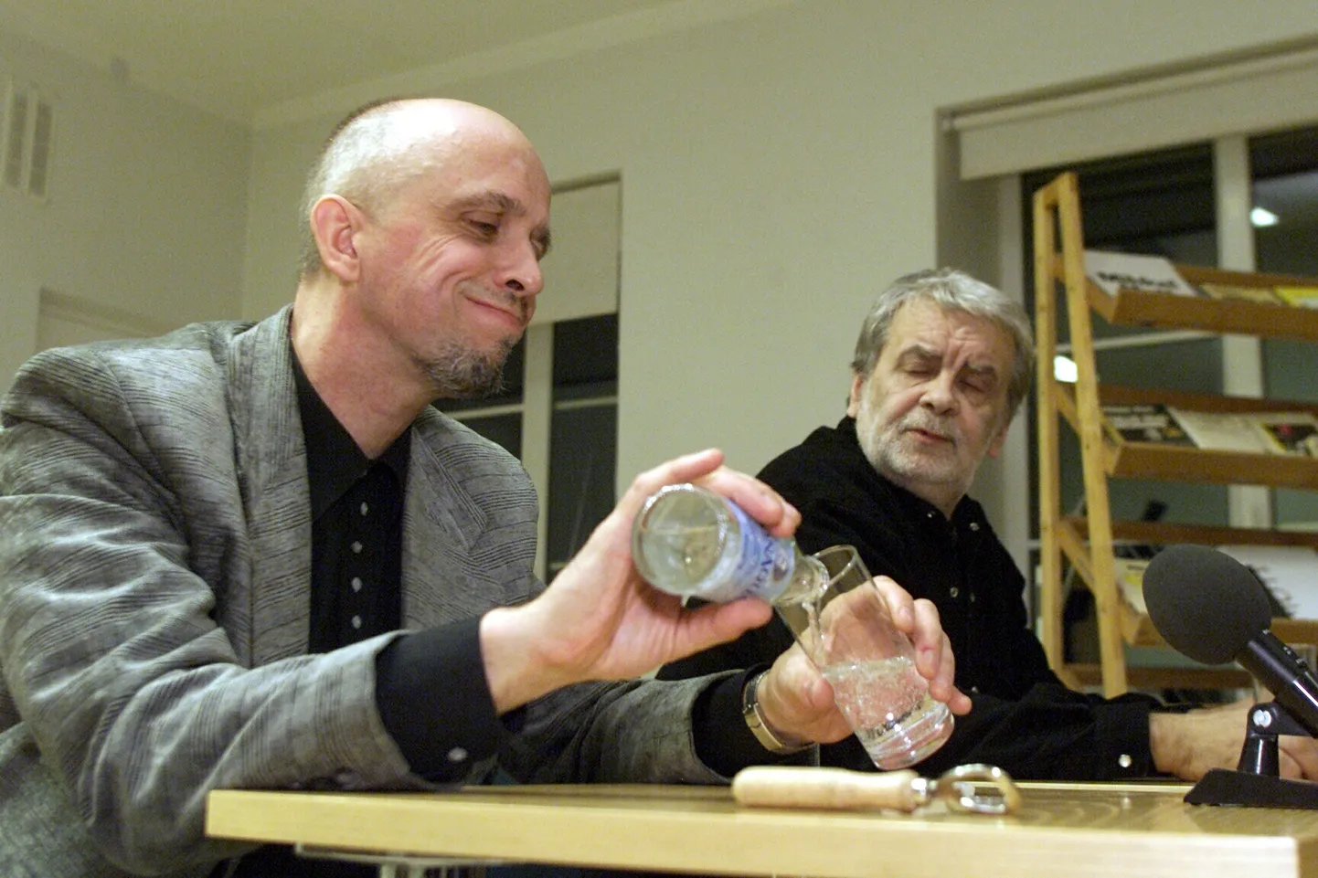 Mihkel Mutt kallab 9. novembril 2000 Tartu linnaraamatukogus kohtumisõhtul lugejatega klaasi karastusjooki. Mati Undi pilgust võib arvata, et ka tema kurk on kuiv.