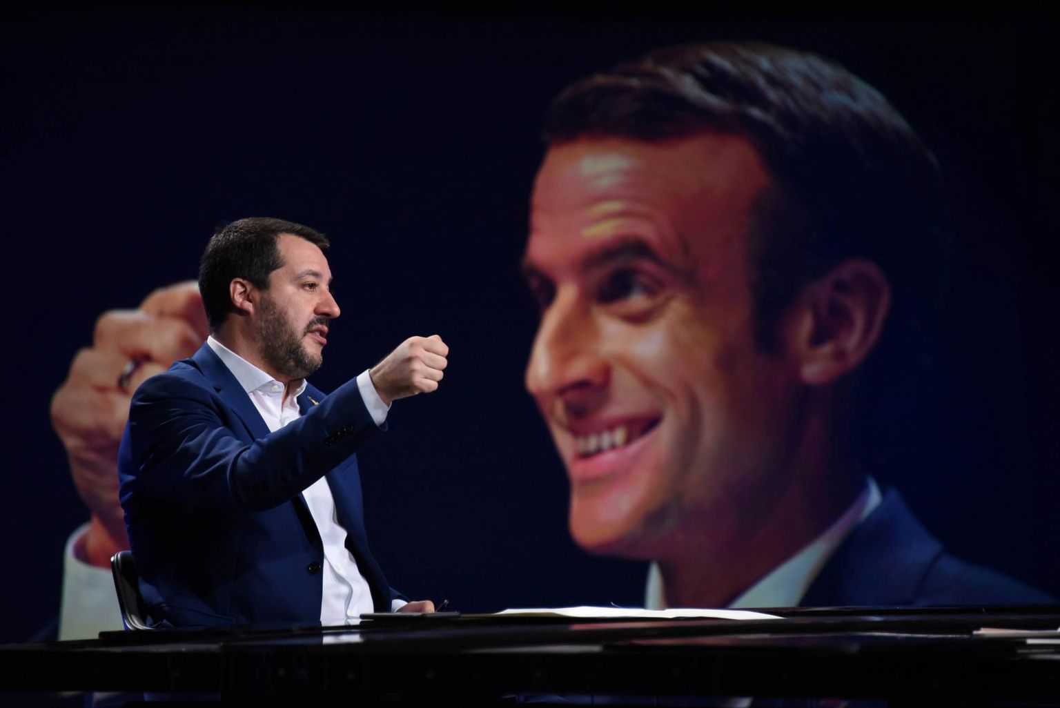 Itaalia siseminister Matteo Salvini (vasakul) televisioonis esinemas. Taustal Prantsusmaa president Emmanuel Macron.