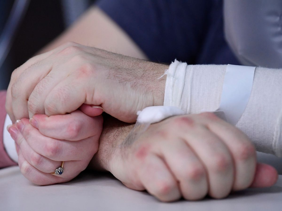 Elizabeth Kerr, 31, and Simon O'Brien, 36, hold hands in a COVID-19 ward, days after they married in an ICU (Intensive Care Unit) when both had become critically ill with the coronavirus disease (COVID-19), and were uncertain of their chances of surviving, in Milton Keynes University Hospital, Milton Keynes, Britain, January 20, 2021. Picture taken January 20, 2021. REUTERS
