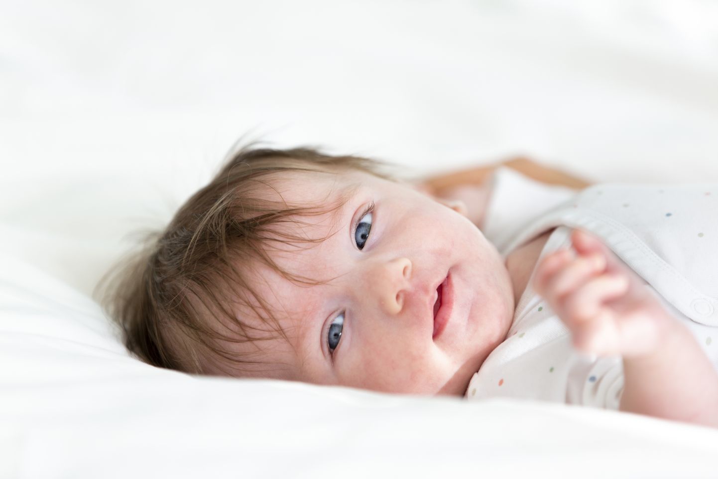 three month old, cute baby with dotted body is lying in bed