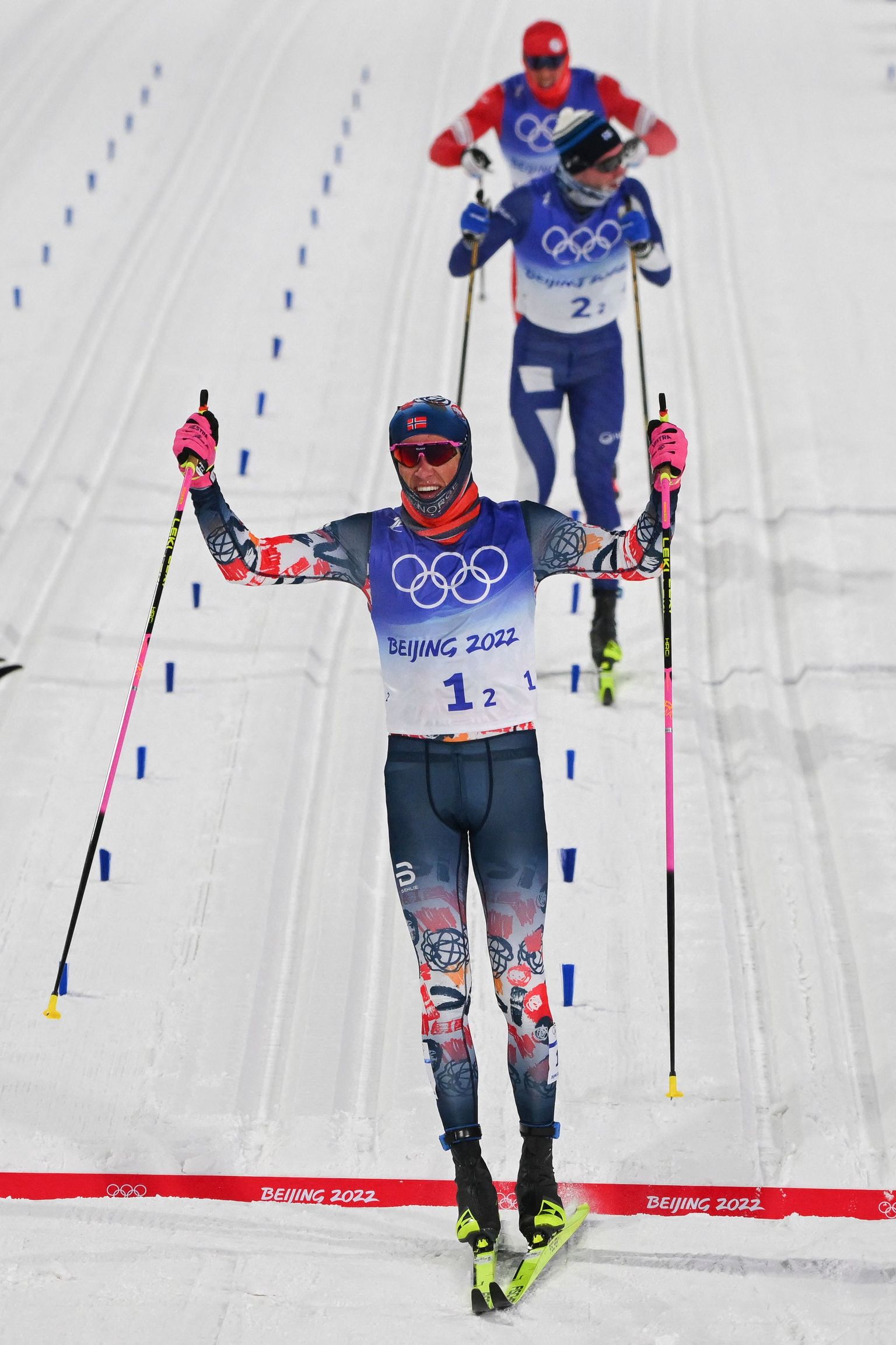 Norway's Johannes Hoesflot Klaebo (Front) celebrates as he crosses the finish line ahead of Finland's Joni Maki (Rear C) for Norway to win the men's team sprint classic final event during the Beijing 2022 Winter Olympic Games on February 16, 2022, at the Zhangjiakou National Cross-Country Skiing Centre. (Photo by Pierre-Philippe MARCOU / AFP)