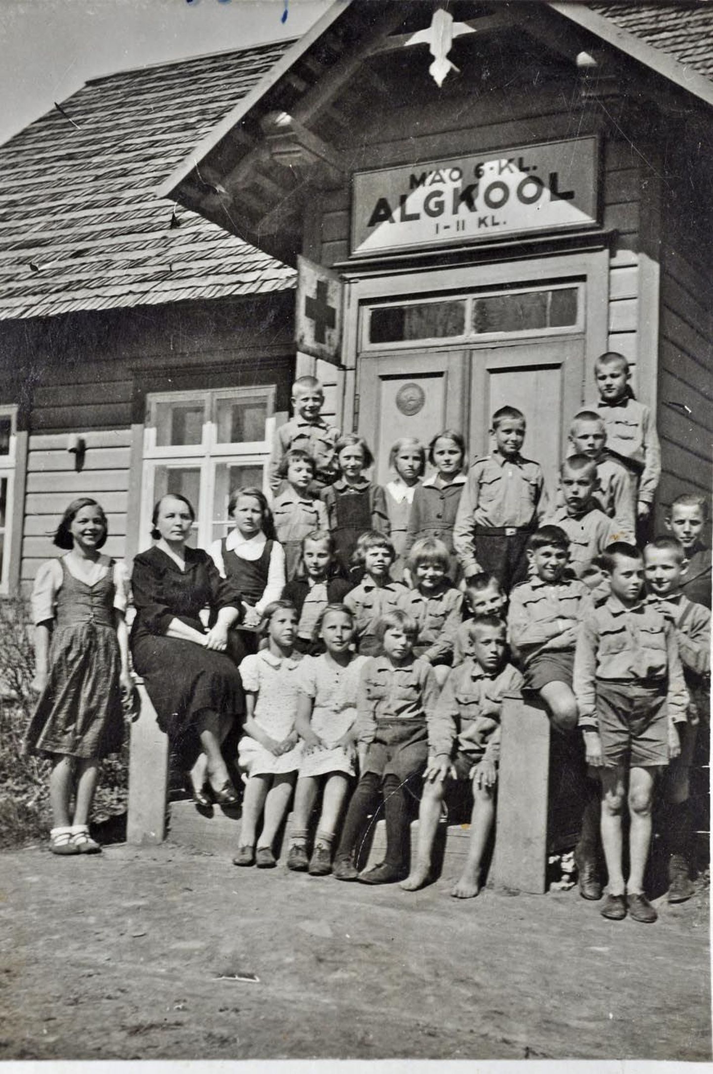Koolimaja asus üsna raudtee ääres ühe kilomeetri kaugusel Mäo mõisast. Selles puidust ühekorruselises koolihoones õppisid vaid esimese ja teise klassi õpilased. Kooli juhatas preili Loosaar, kes istub samuti trepil õpilaste keskel. 1940