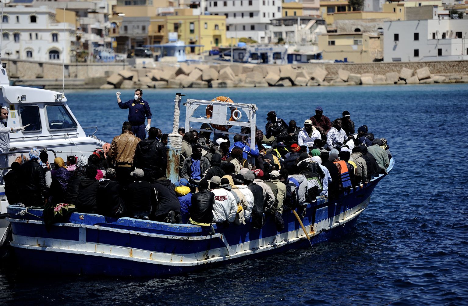 Итальянская полиция эскортирует судно с ливийскими беженцами у берегов острова Лампедуза.