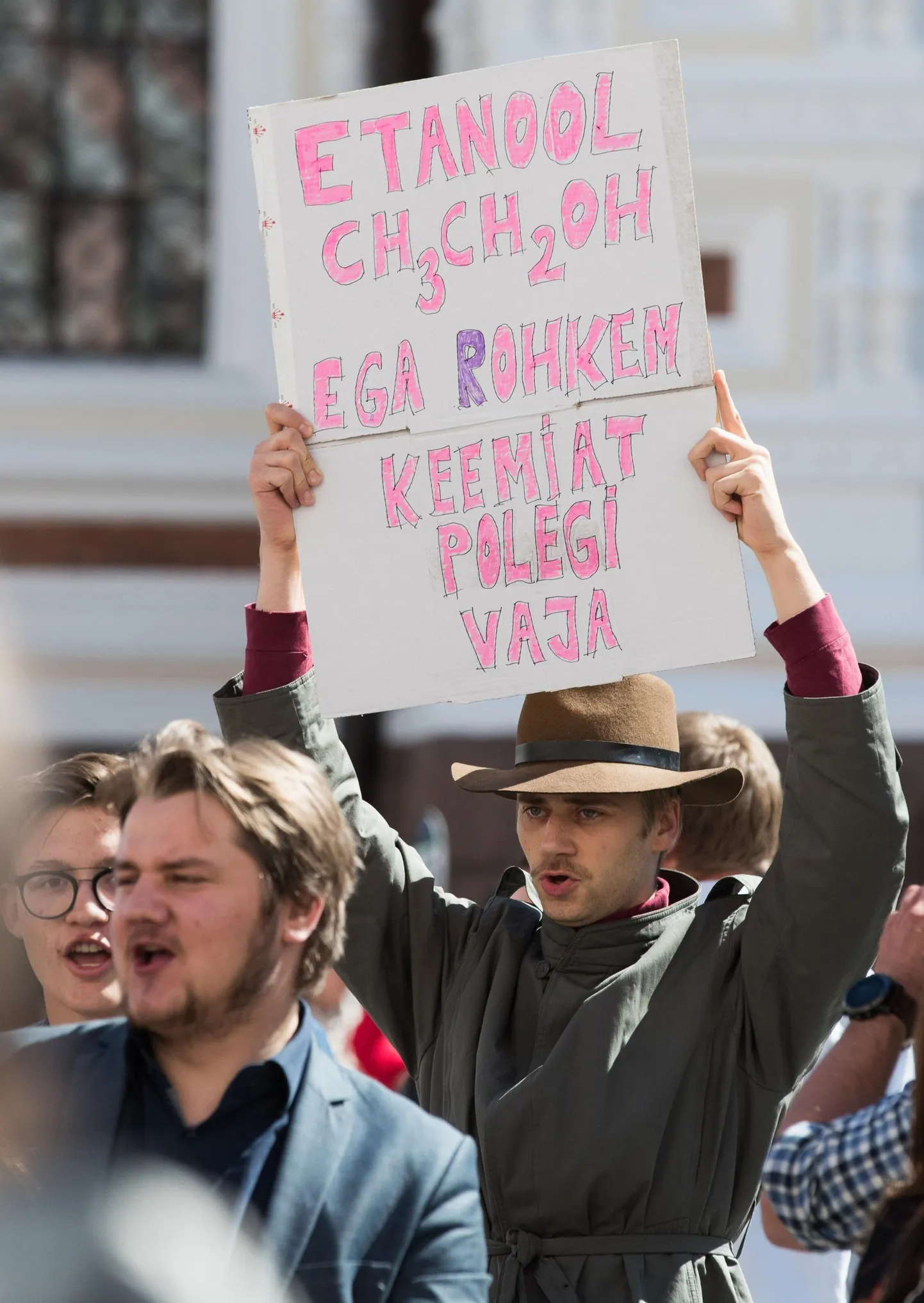 Teadlane teaduspõlgurit naeruvääristava plakatiga.