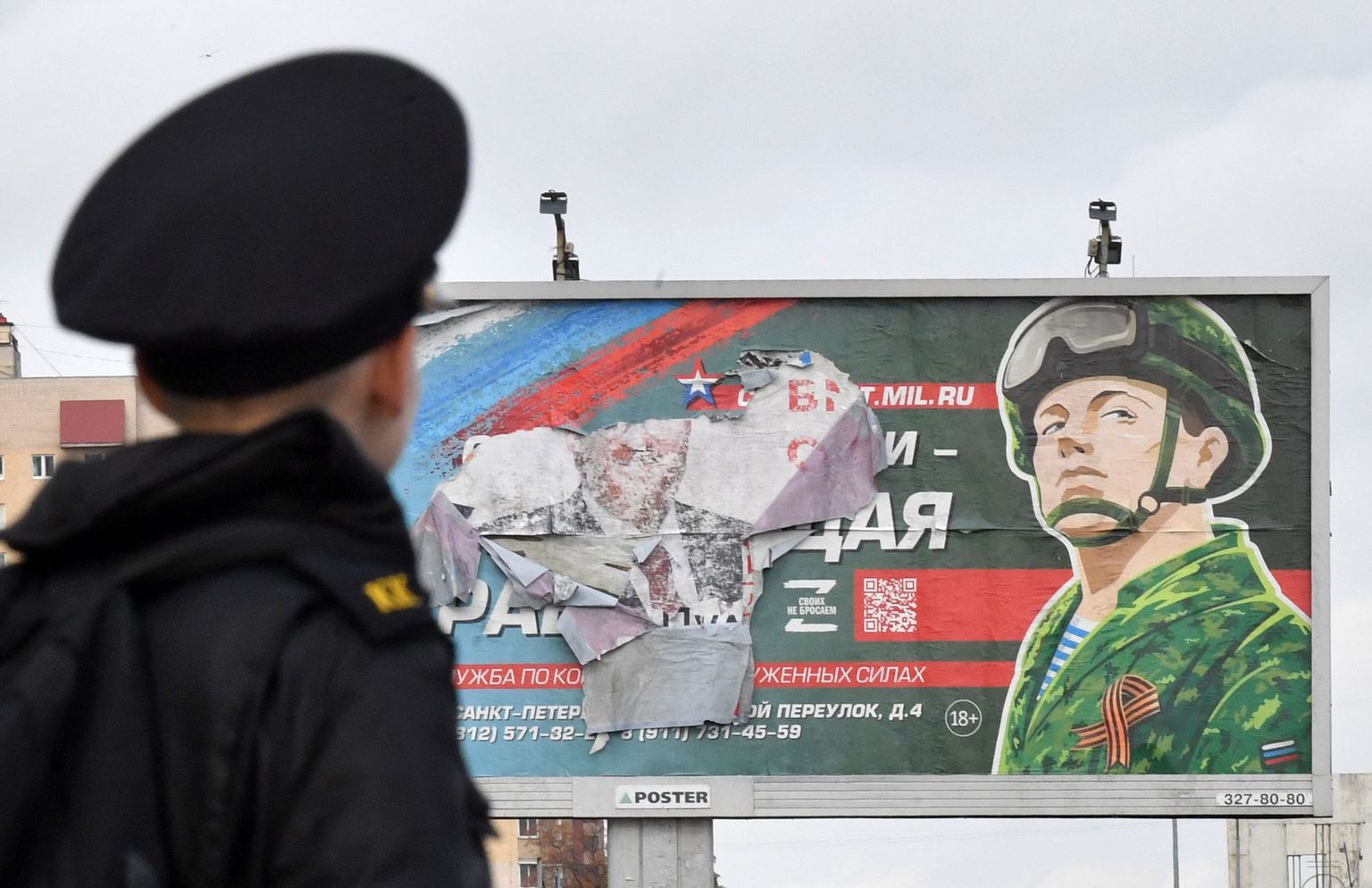 Kadett Peterburis sõjaväeteenistust propageeriva plakati ees.
